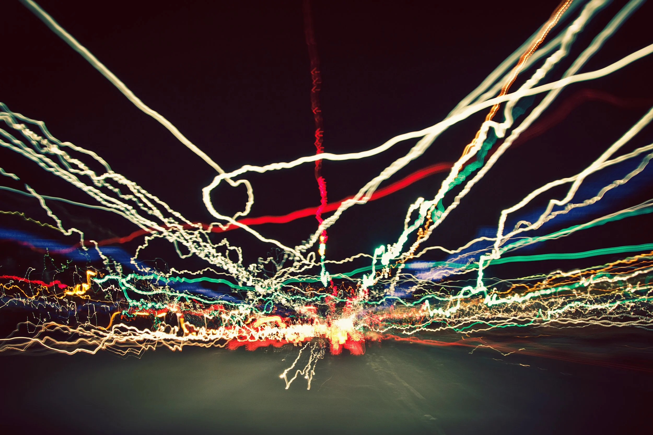 Abstract long exposure photograph of colorful light streaks at night, creating a chaotic pattern.