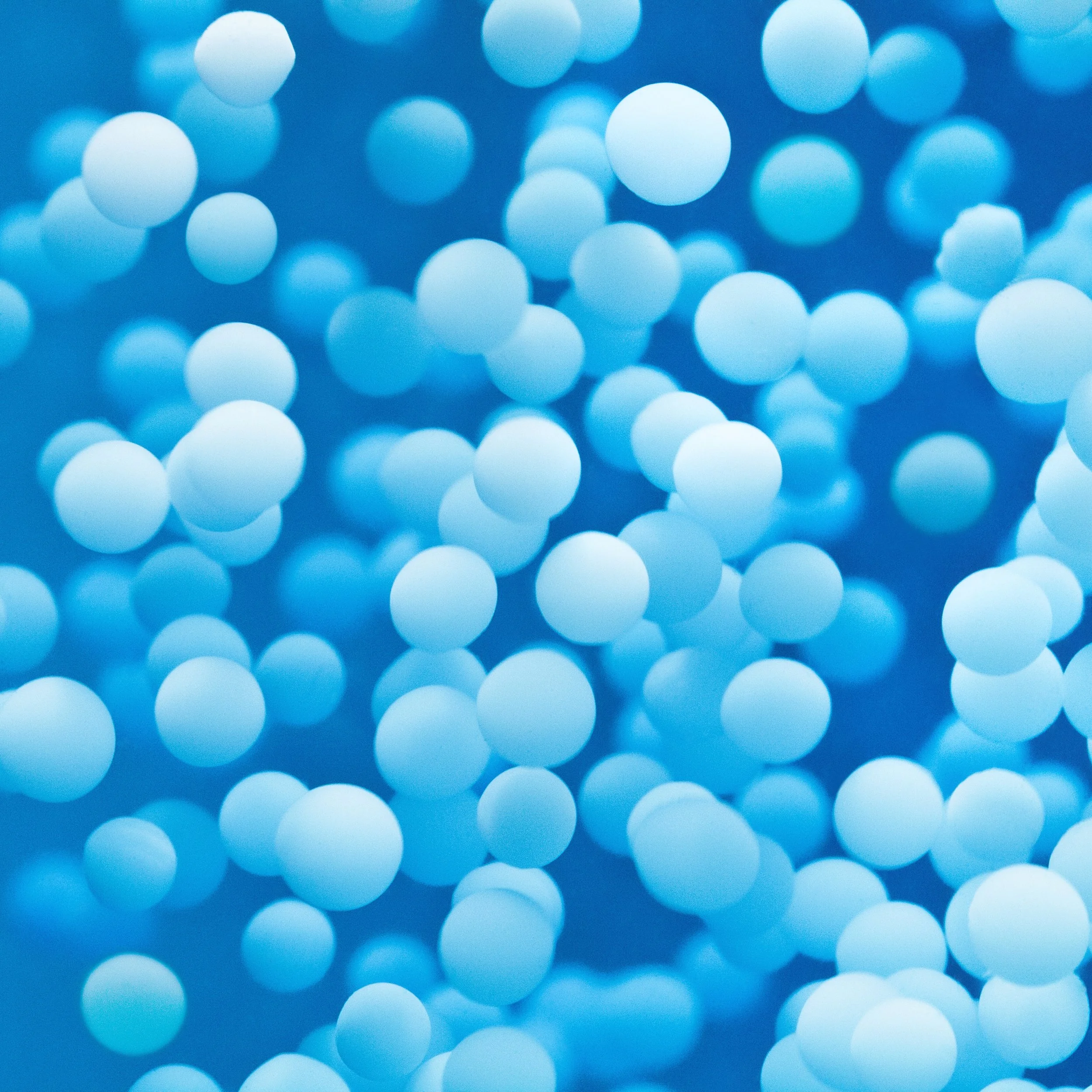Close-up of numerous small, light blue foam balls with a blurred background.