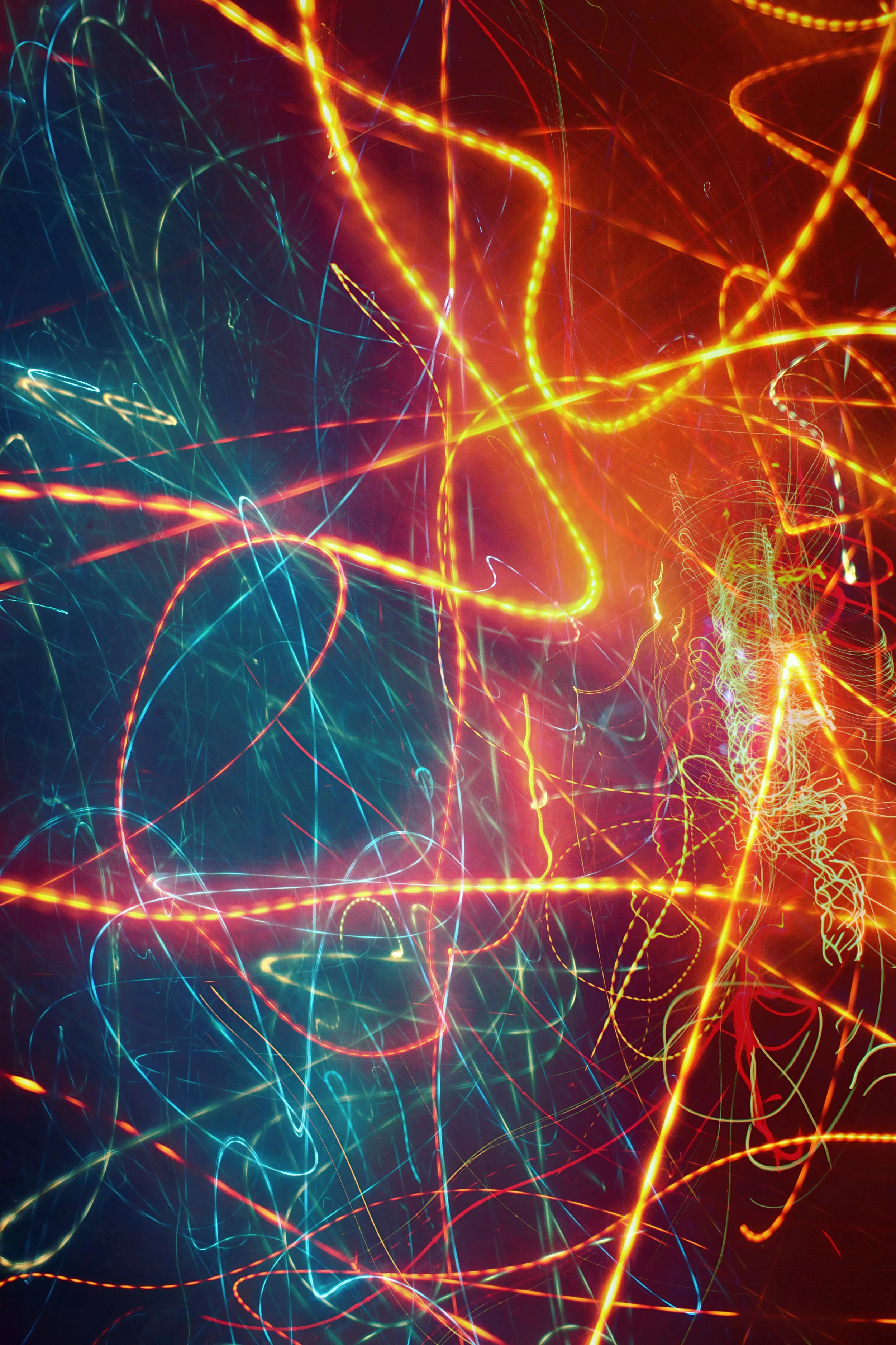 Abstract long exposure photograph of multicolored light trails against a dark background.