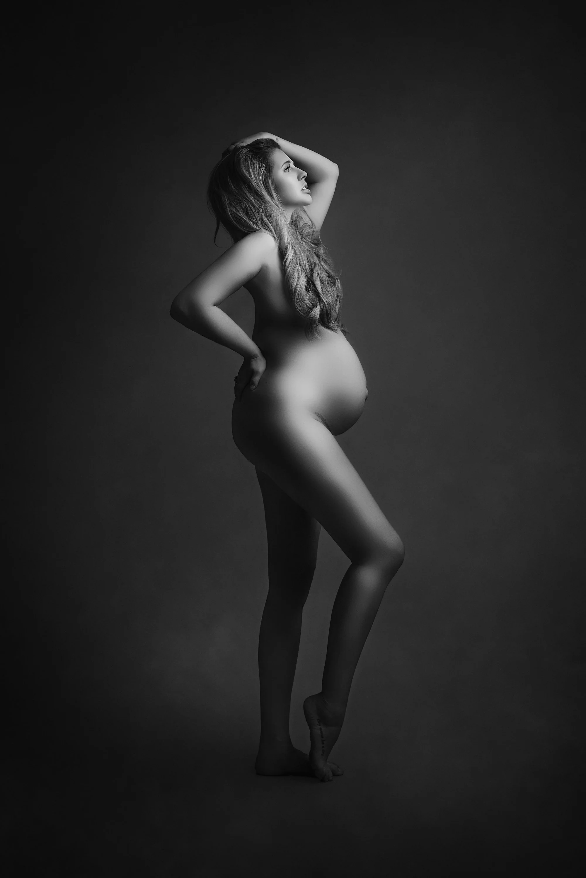 nude pregnant lady gracefully holding her head and back