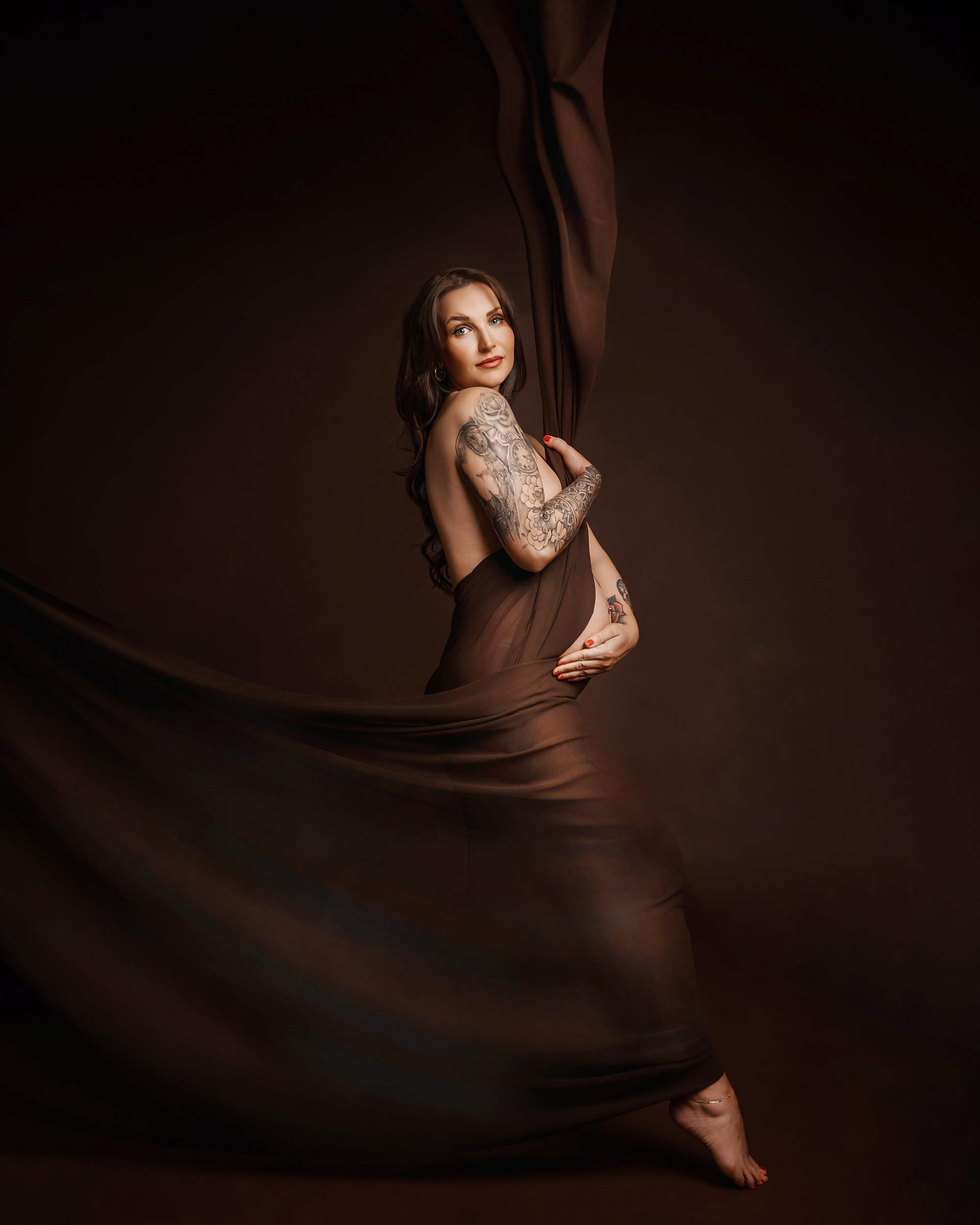 pregnant woman draped in brown fabric photographed at kath evans photography studio talgarth brecon mid wales