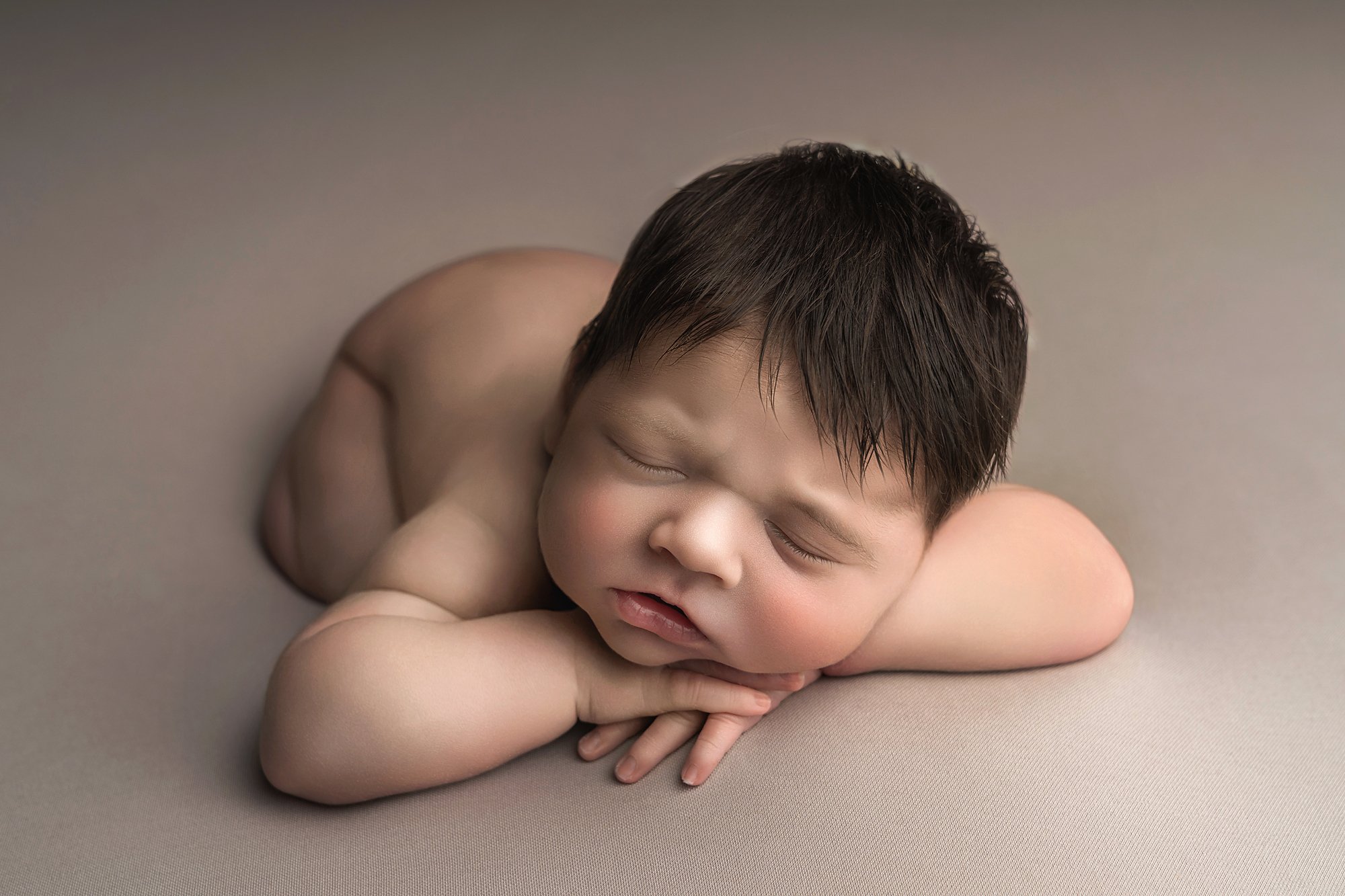 A newborn baby boy sleeping with his arms folded under his chin photographed at kath evans photography studio talgarth brecon mid wales