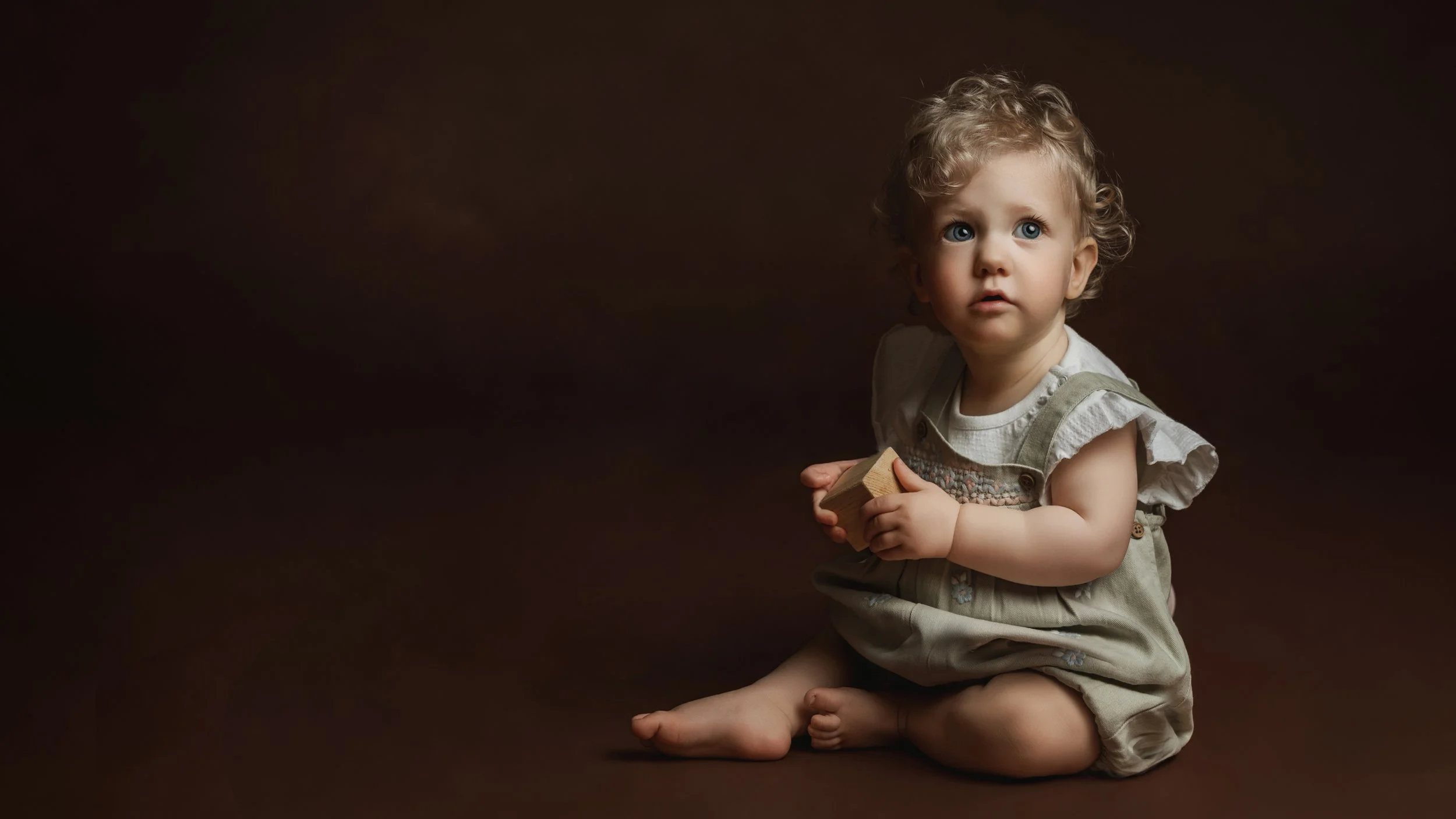 A LITTLE GIRL SITTING WITH A TOY