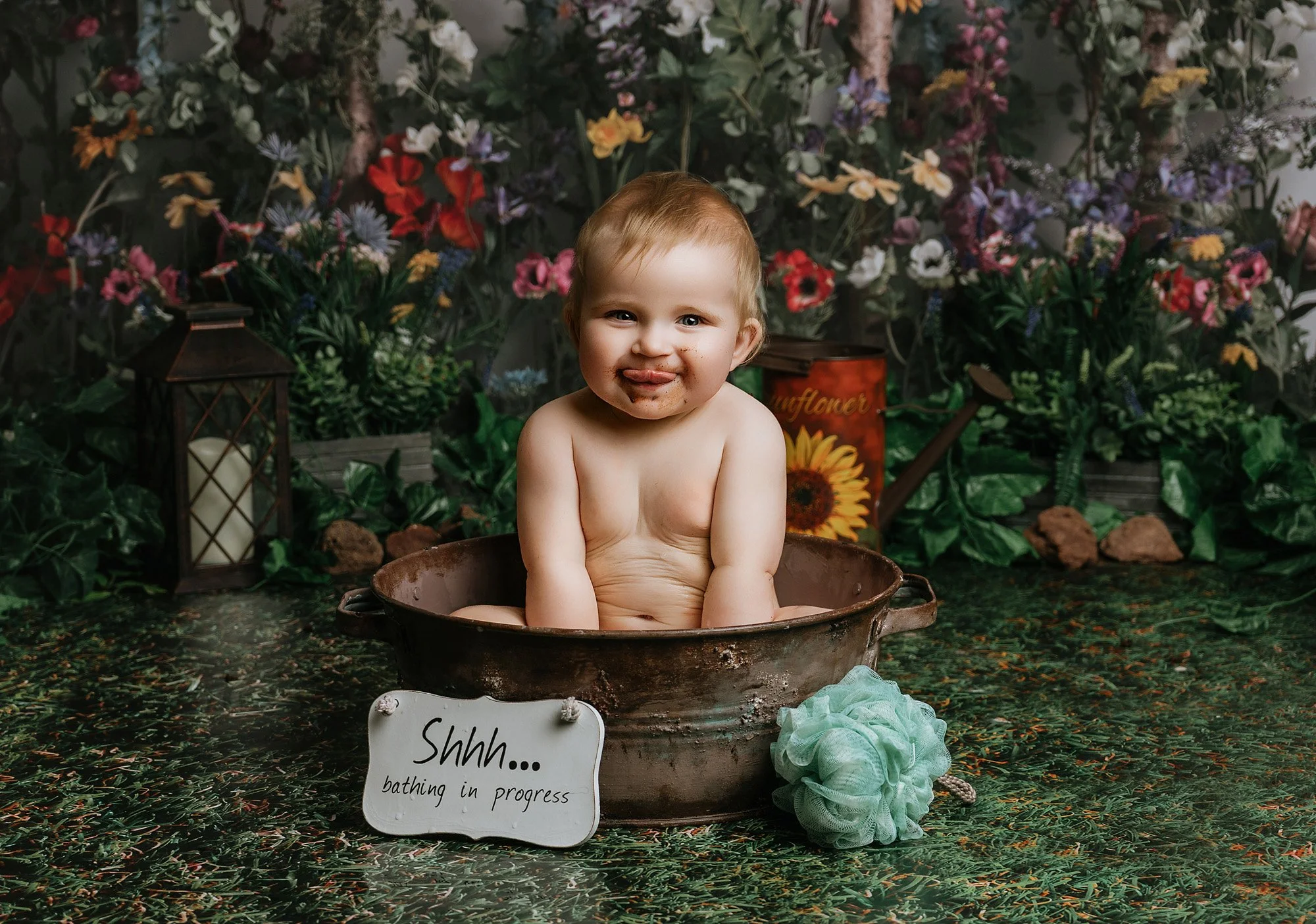 A young child sitting in a vintage metal tub filled with water, smiling photographed at kath evans photography studio talgarth brecon mid wales.