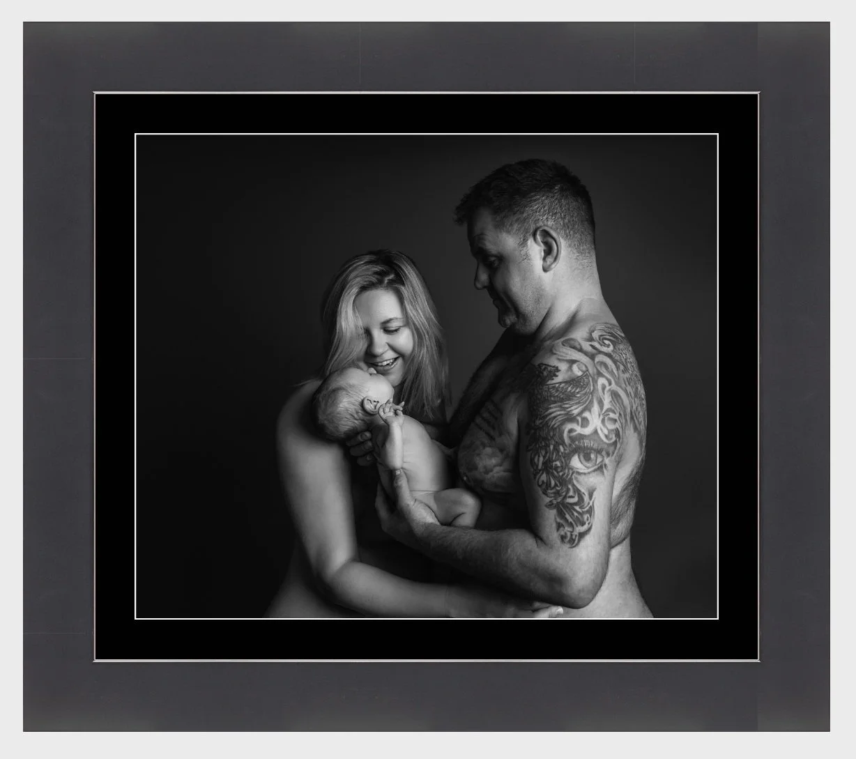 Sleeping baby wearing a knitted bonnet, holding a small knitted teddy bear, on a beige surface.