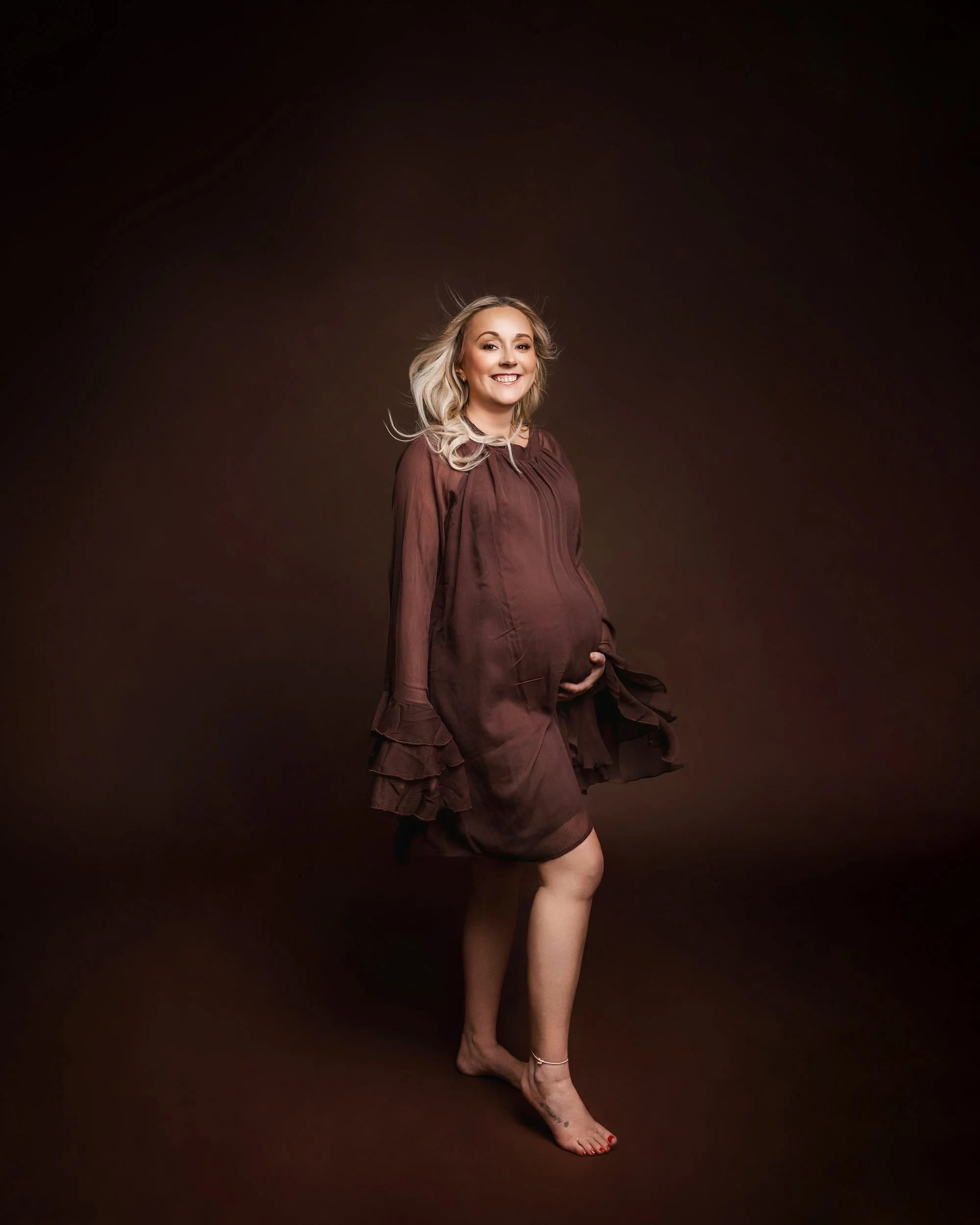 pregnant woman in brown dress photographed at kath evans photography studio talgarth brecon mid wales