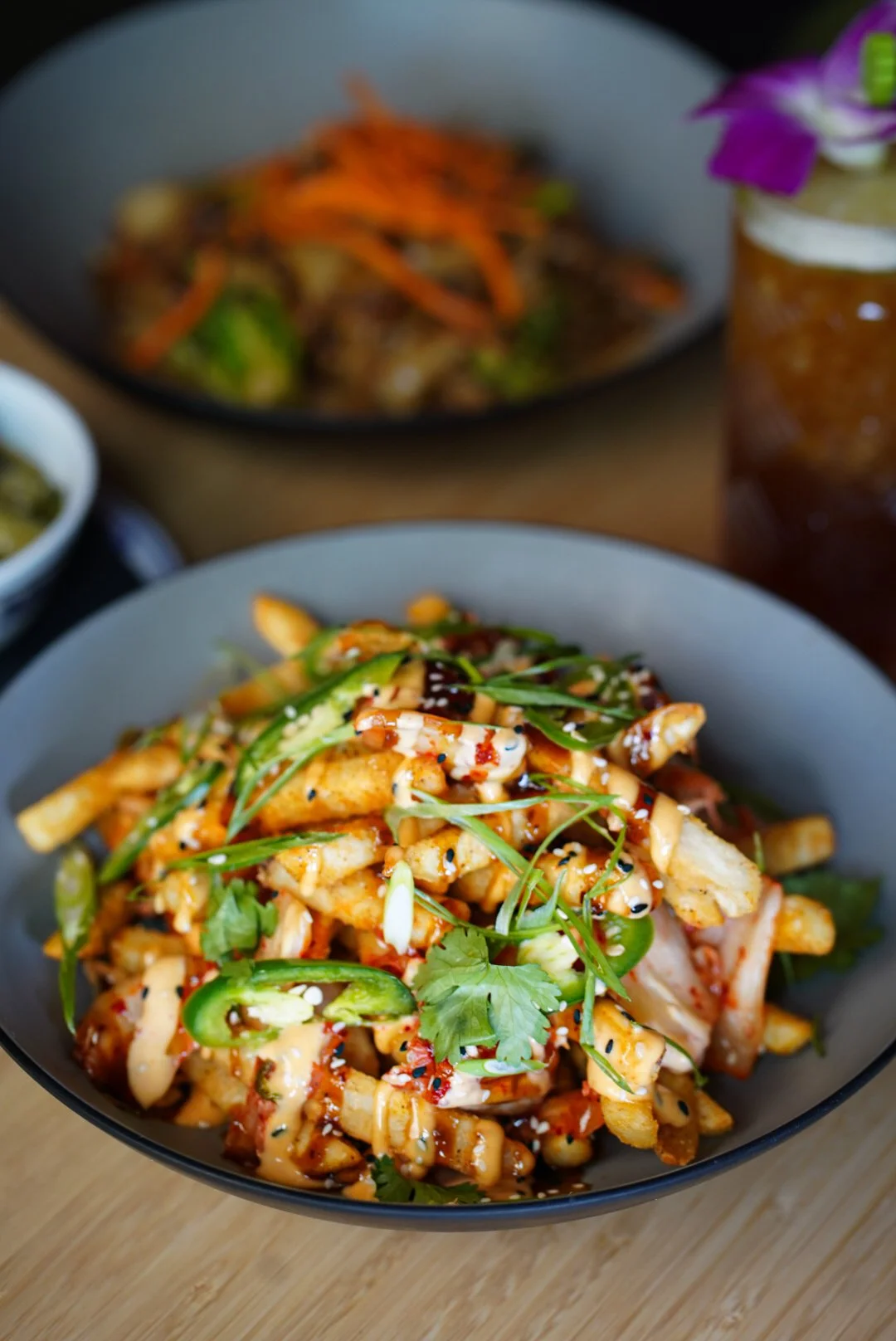Close-up of a bowl of Asian-style chicken and noodle salad topped with cilantro and sliced green chili peppers.
