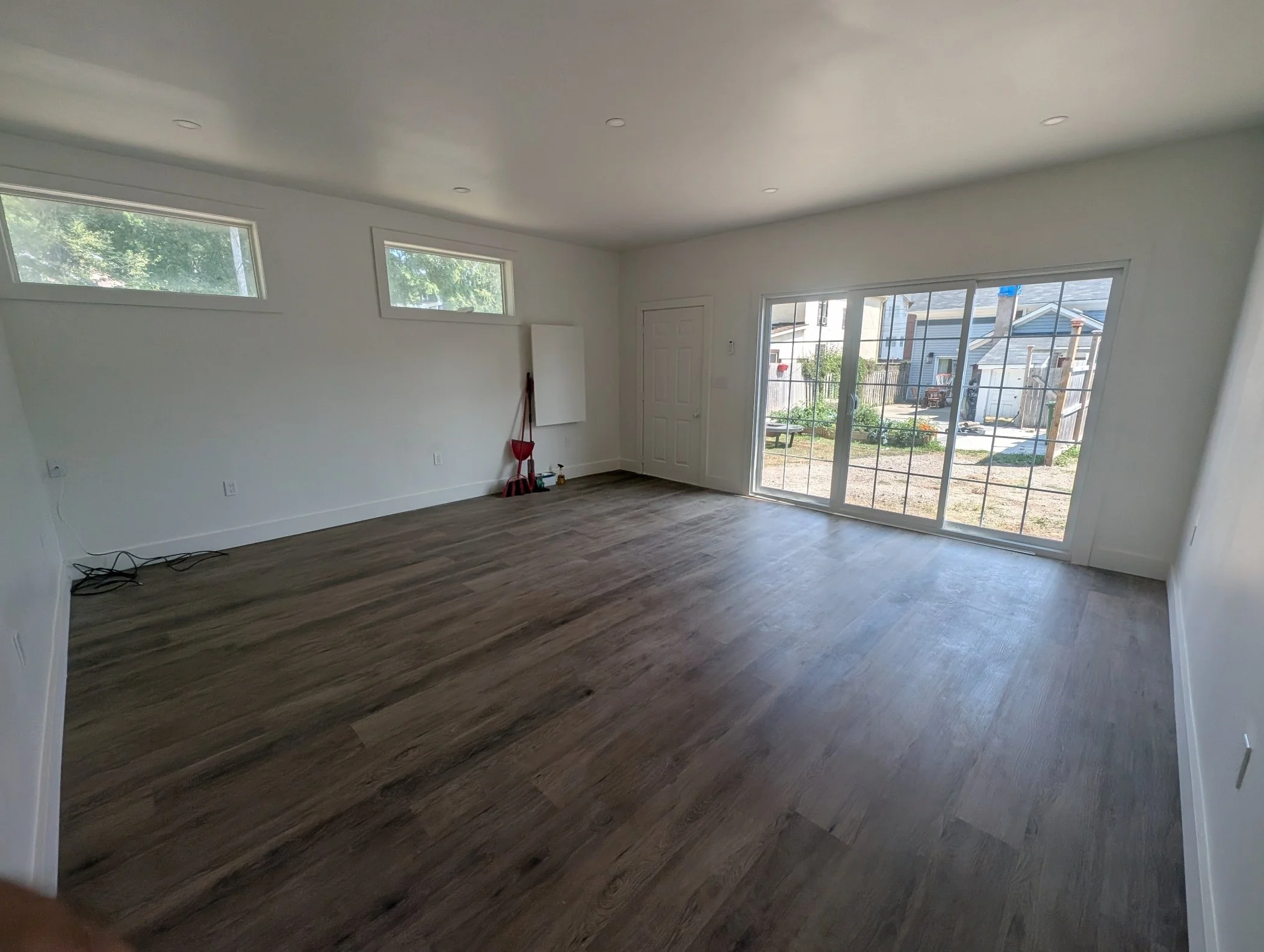 Living room with sliding glass doors, small windows, hardwood floors, and white walls.