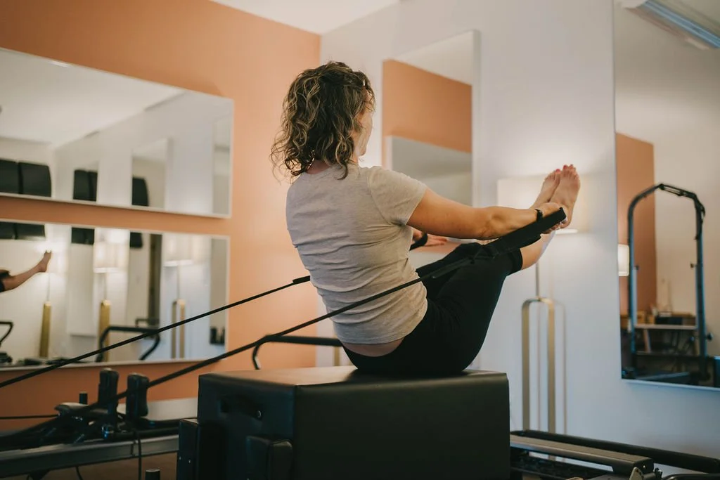 Women doing a pilates class on reformer machines in a studio.