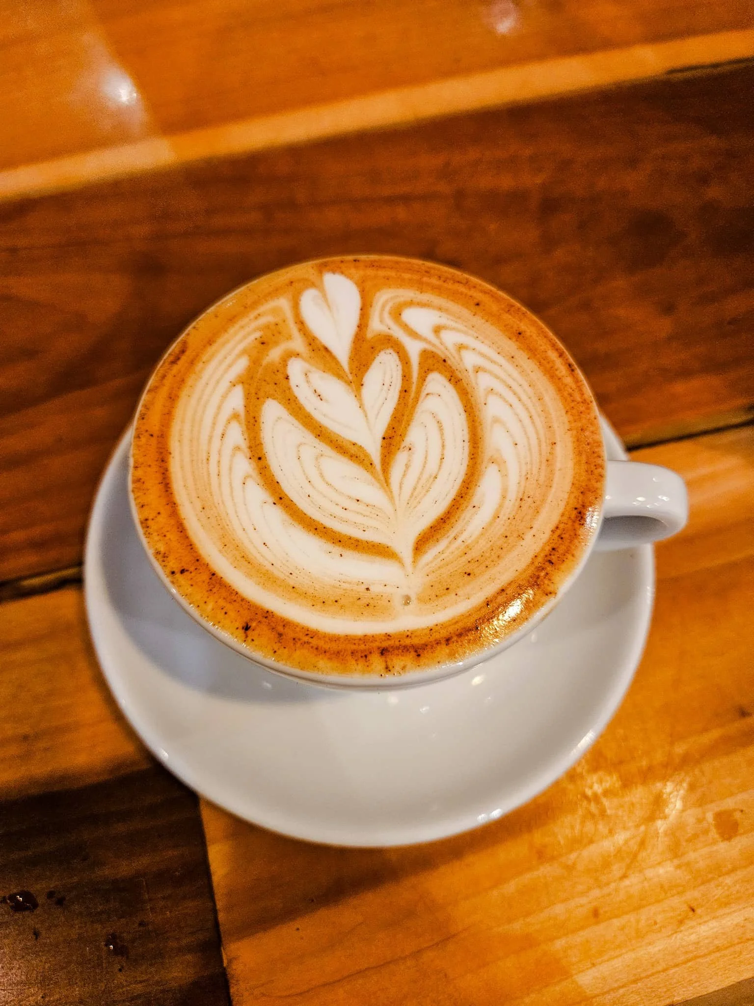 Cup of coffee with latte art on wooden table.
