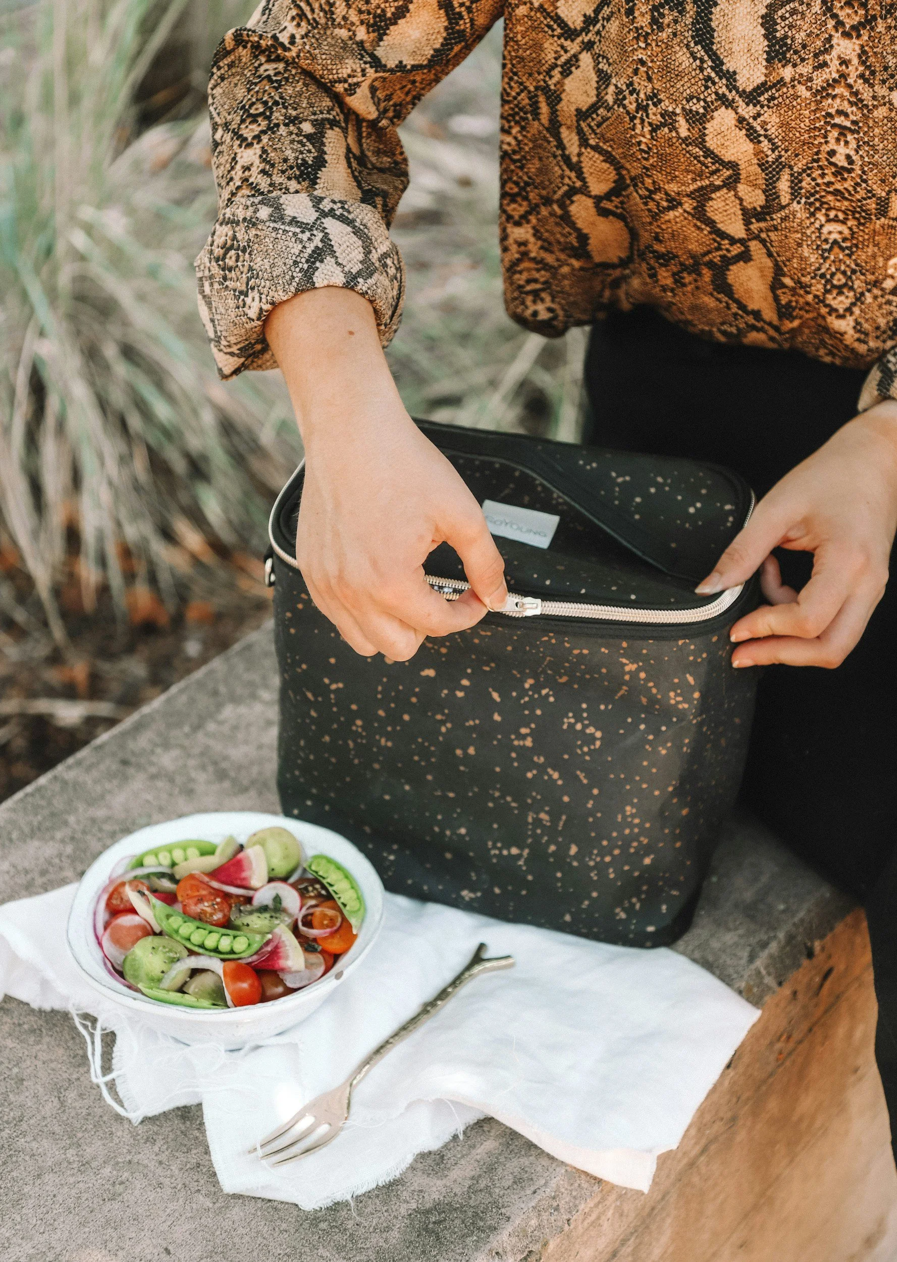 Girl with a lunchbox, salad, and fork on a table