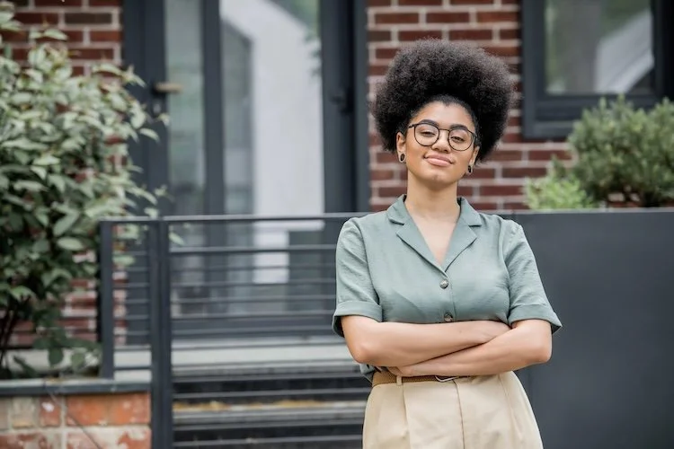 Confident woman of color standing outside. Gentle Joy Sensitive Women's Leadership Collective with Lori Cangilla from Singularly Sensitive