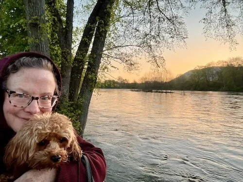 Singularly Sensitive creator Lori L. Cangilla PhD Licensed Psychologist Certified Forest Therapy Guide (CFTG) author mentor coach on a forest therapy walk in Allegheny National Forest north of PIttsburgh PA spring sunset Allegheny River  with her dog