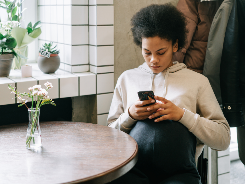 A woman staring at her phone with a tense, anxious expression, illustrating reassurance-seeking behavior