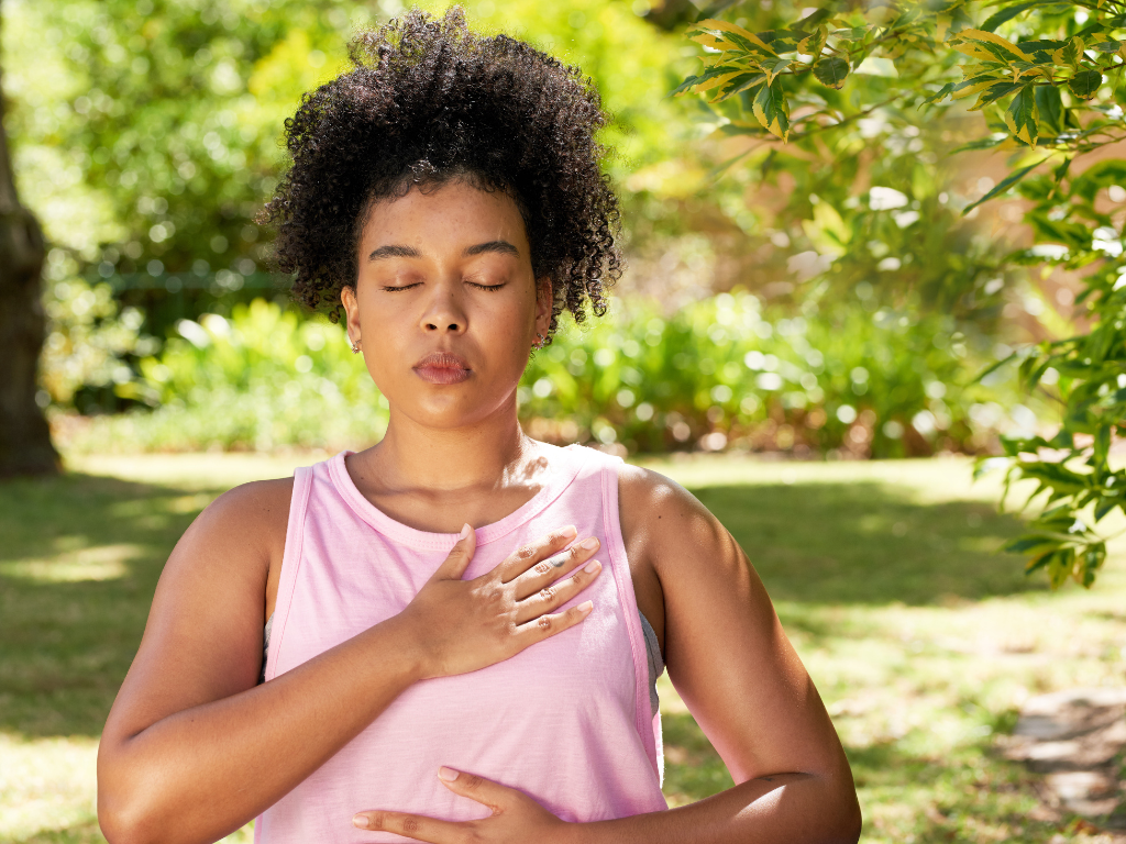 A woman sitting calmly at home practicing deep breathing to reduce anxiety and regulate her nervous system