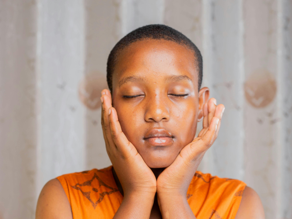 A woman with her eyes closed and hands wrapped around a mug, conveying the quiet exhaustion of perfectionism and people-pleasing