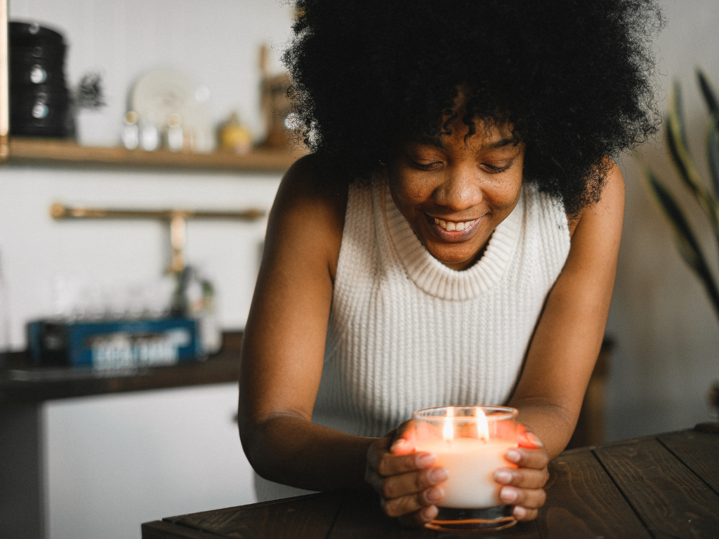 Happy Black girl enjoying a peaceful moment with a candle, promoting mindfulness and mental well-being.