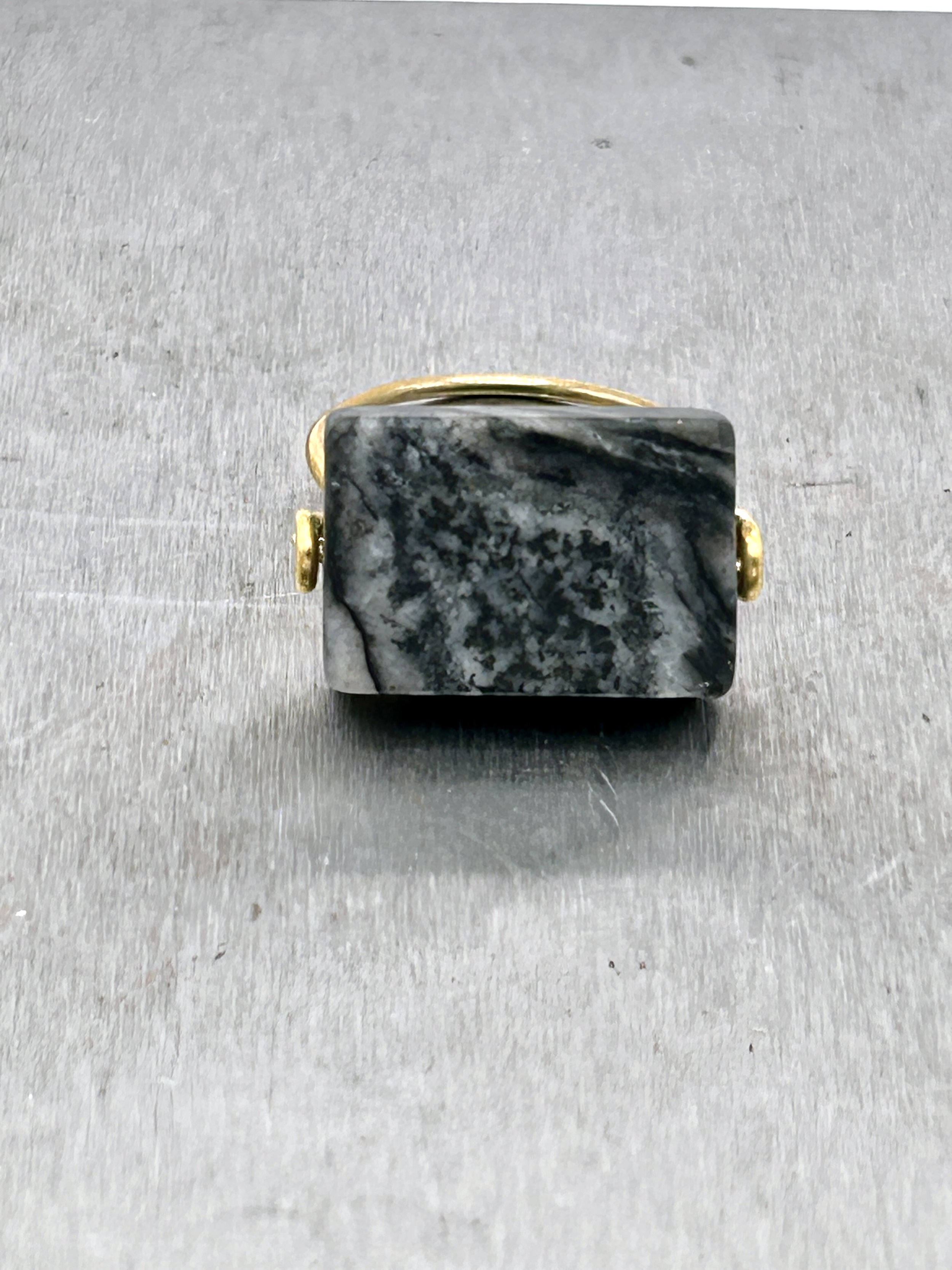 Gray Jungle Jasper rectangle stone on Jeweler's Brass Ring on metal block front view