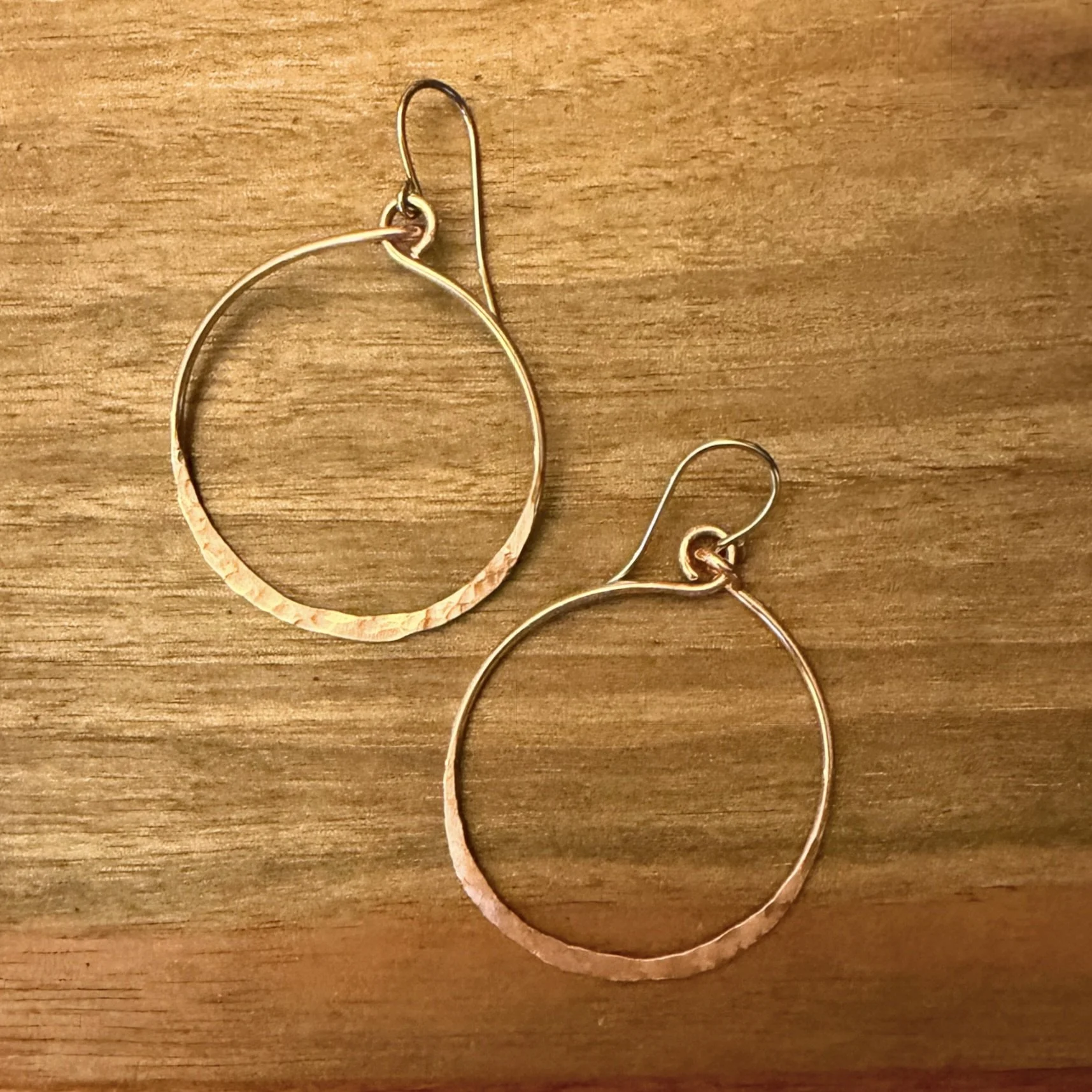 Hammered copper circle earrings on wood