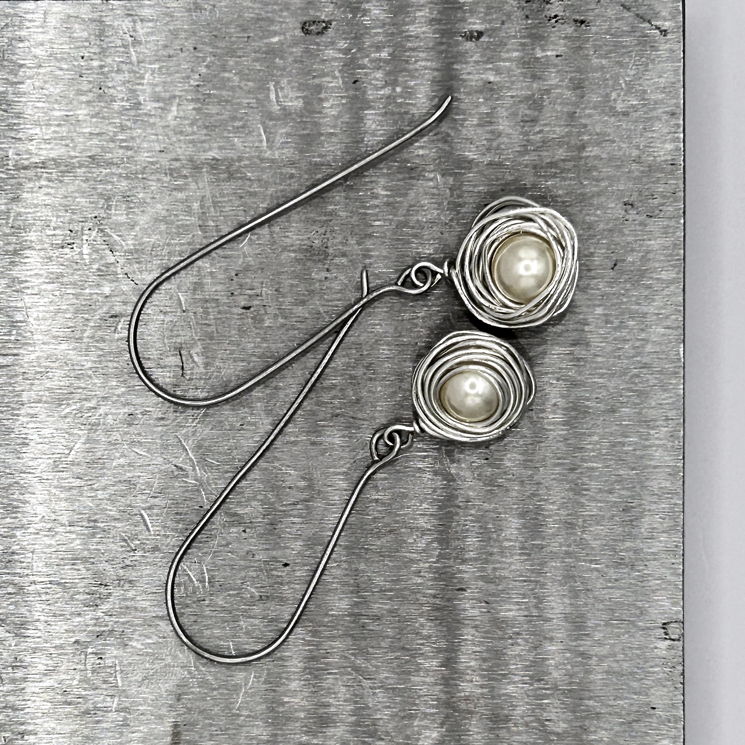 Messy Bun Earring with Pearl Bead nested in Stainless Steel metal and Stainless Steel metal long drop ear wires on metal block