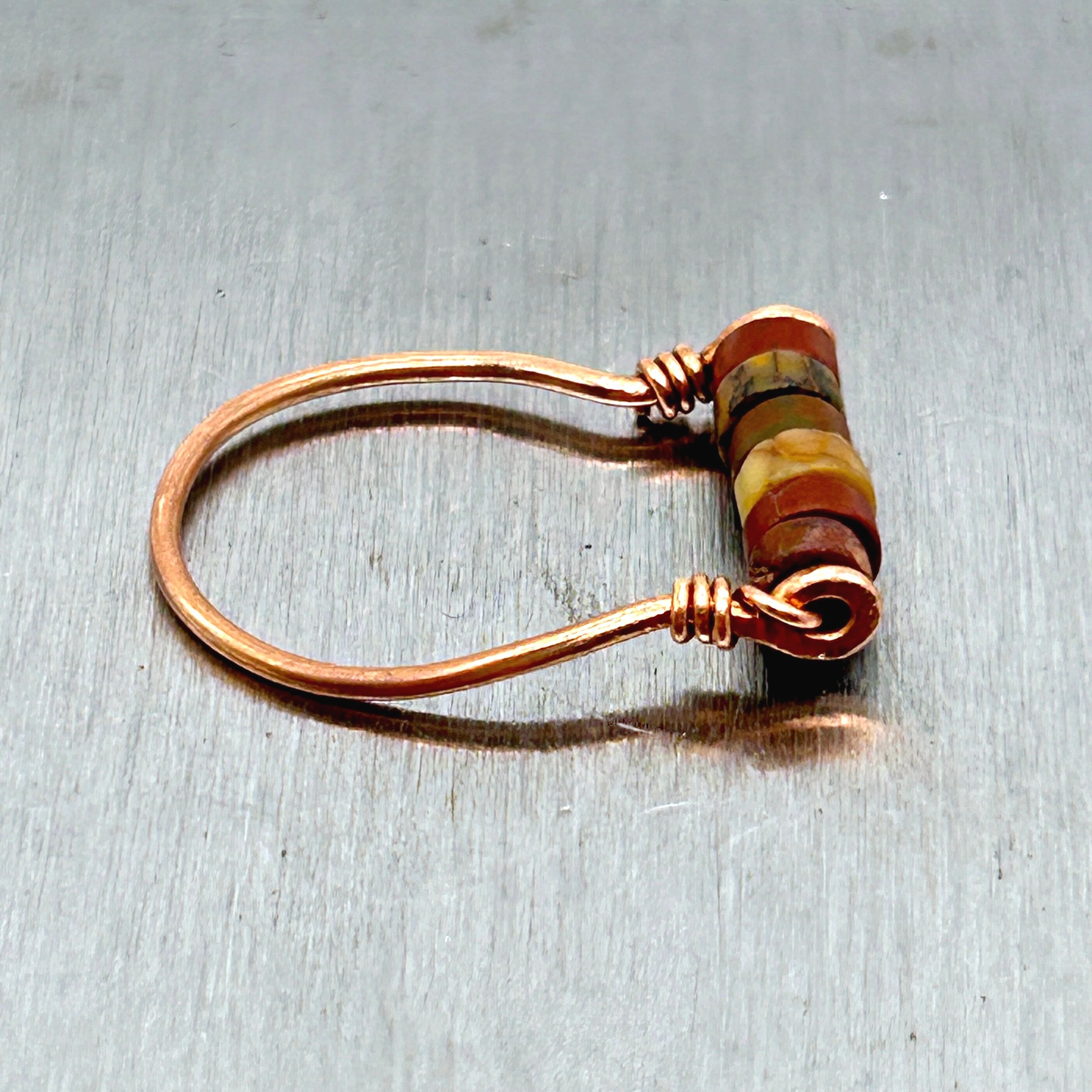 Red Jasper Beads on Copper metal ring on metal block side view