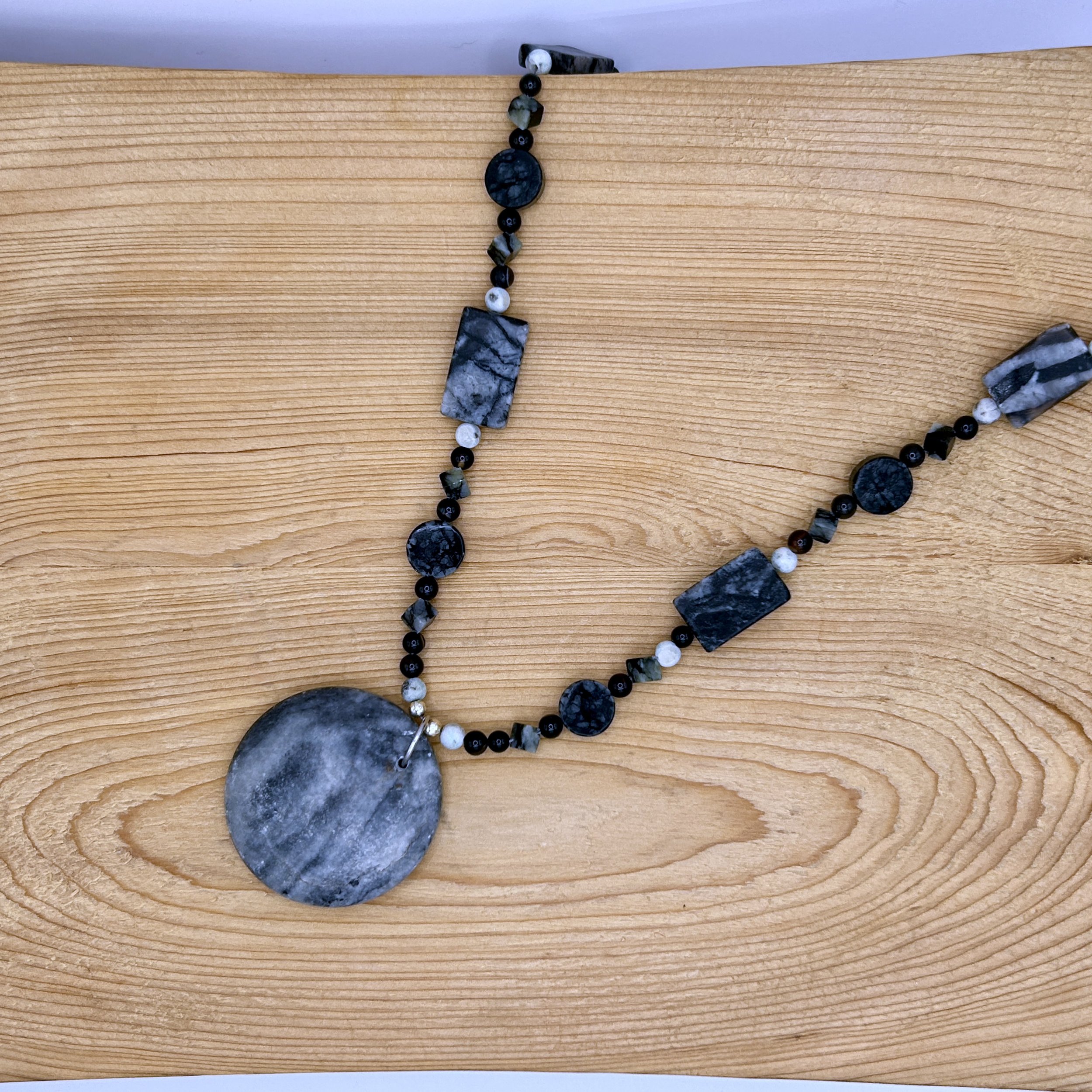 Gemma Black and Gray Marble Pendant Beaded Necklace on wood