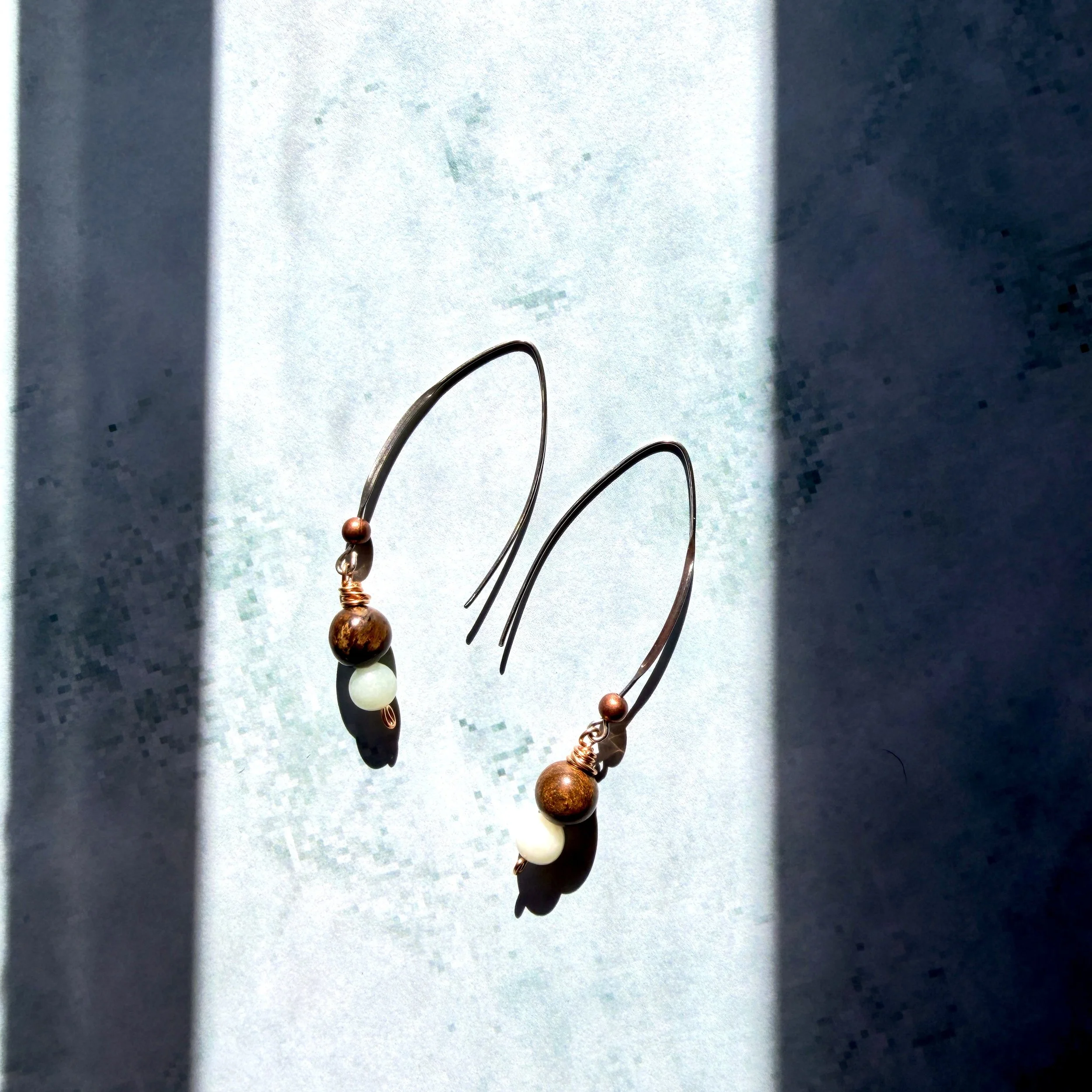 Bronzite and amazonite drop earrings on a pale green backgroun