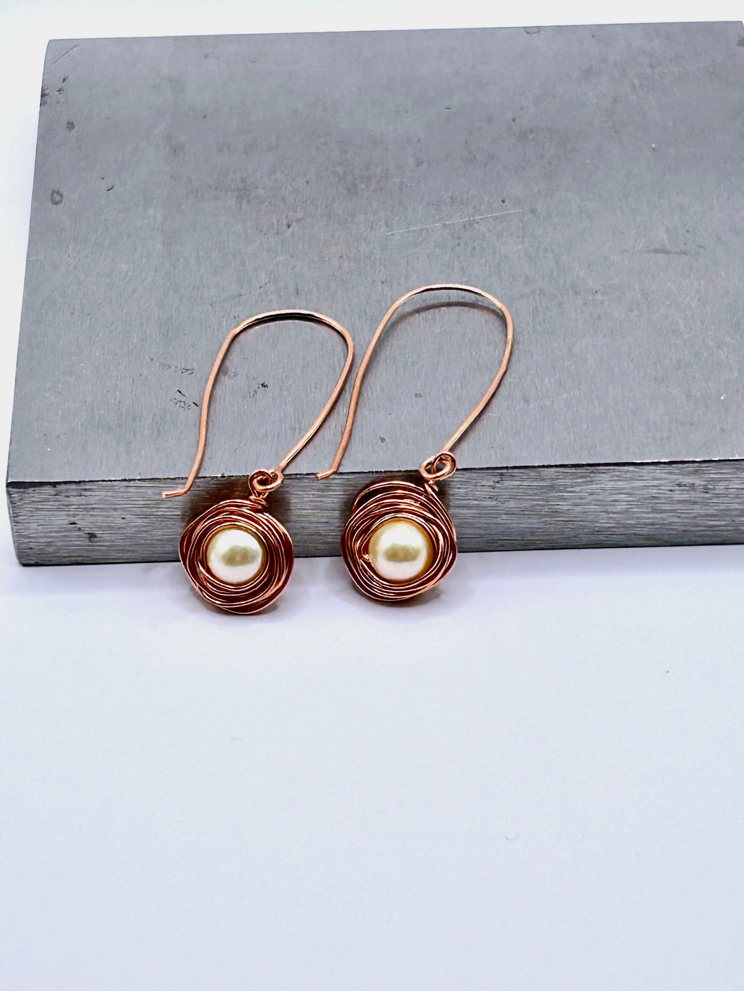 Messy Bun Earring with Pearl Bead nested in Copper metal and Copper metal long drop ear wires on metal block
