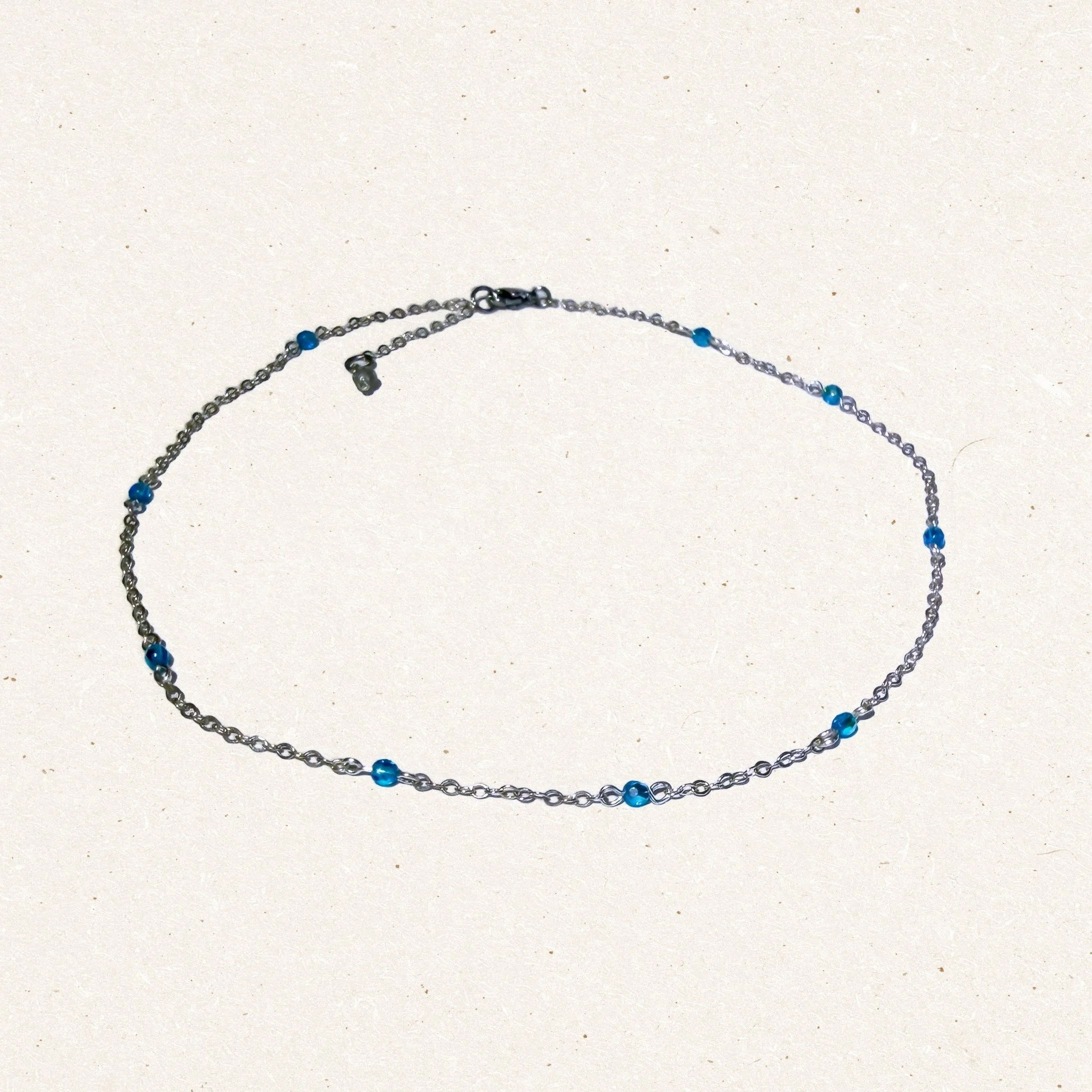 Wrapped Crystal Chain Necklace with Blue Faceted Beads on Light Background
