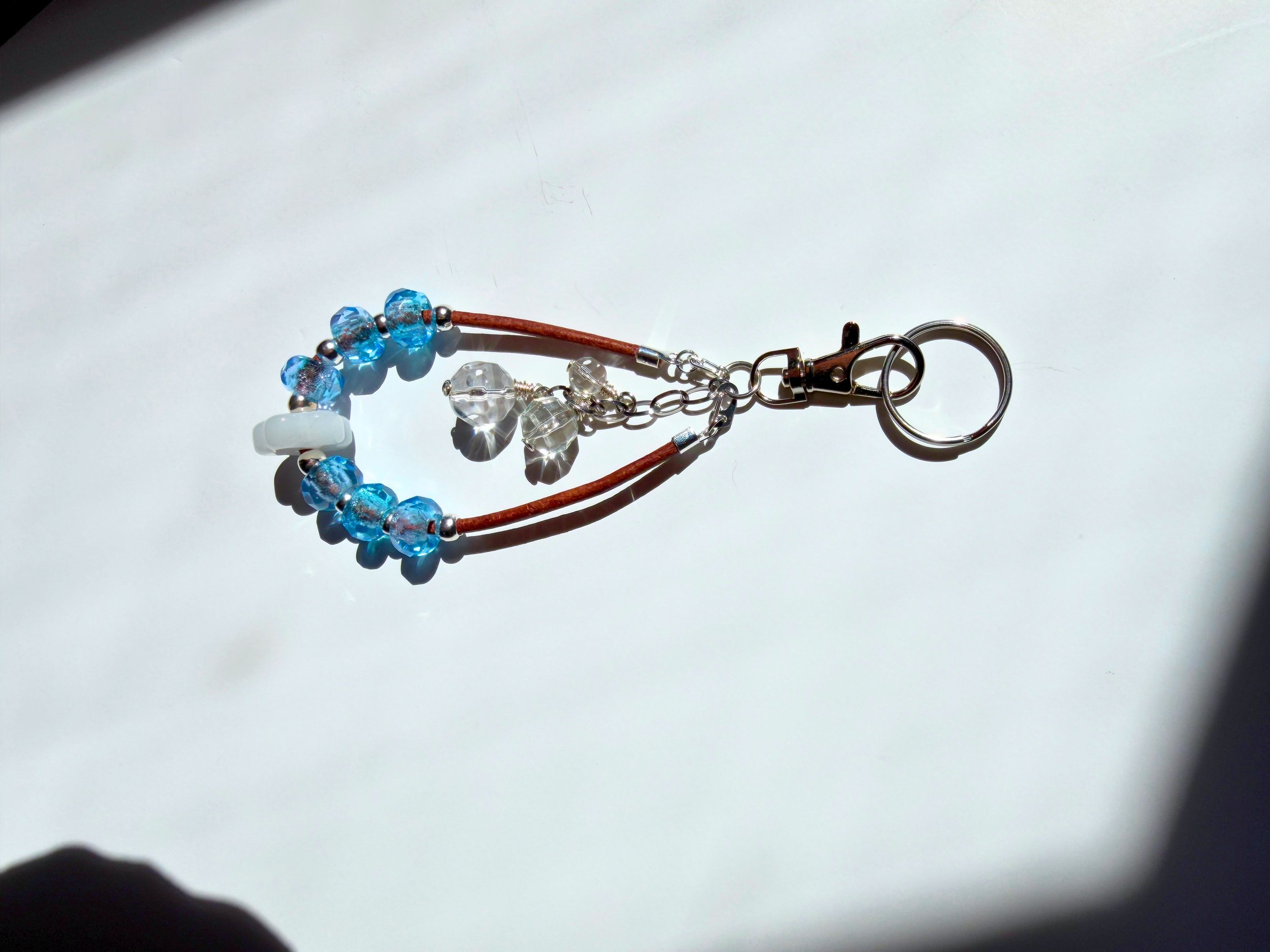 Blue Czech glass and white glass flower, crystal and brown leather bag charm side view on light background