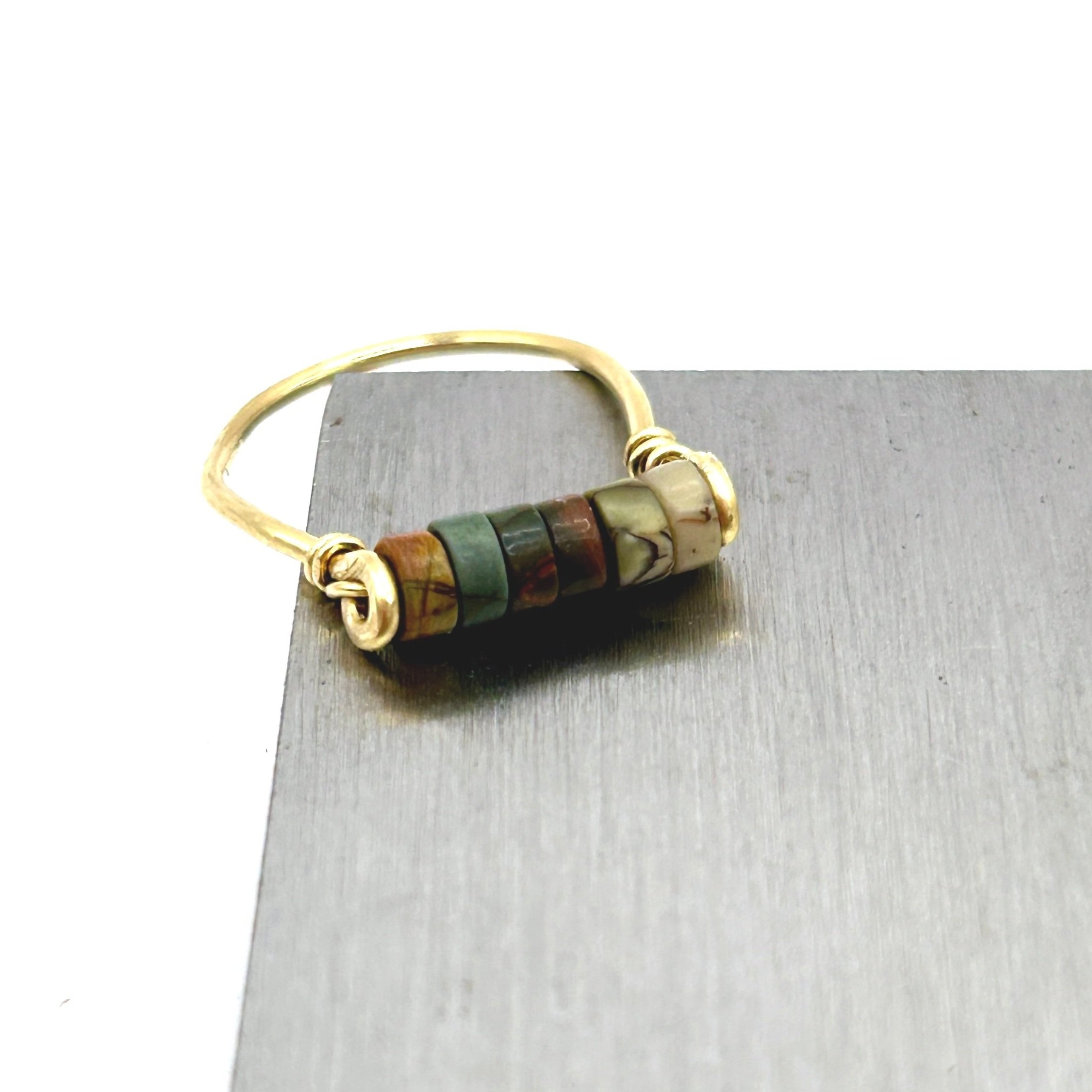 Red Jasper Beads on Jeweler's Brass metal ring on metal block front view