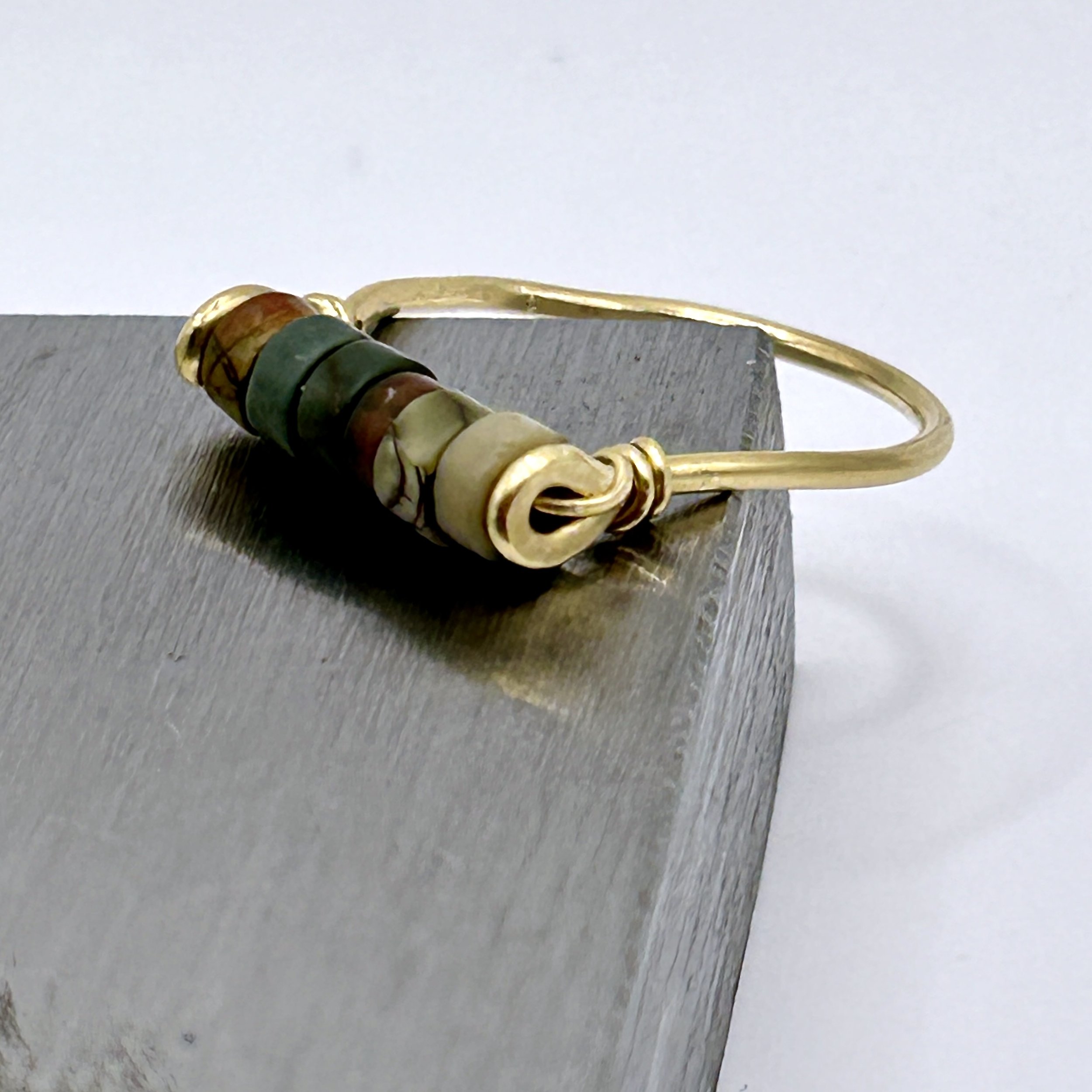 Red Jasper Beads on Jeweler's Brass metal ring on metal block side view