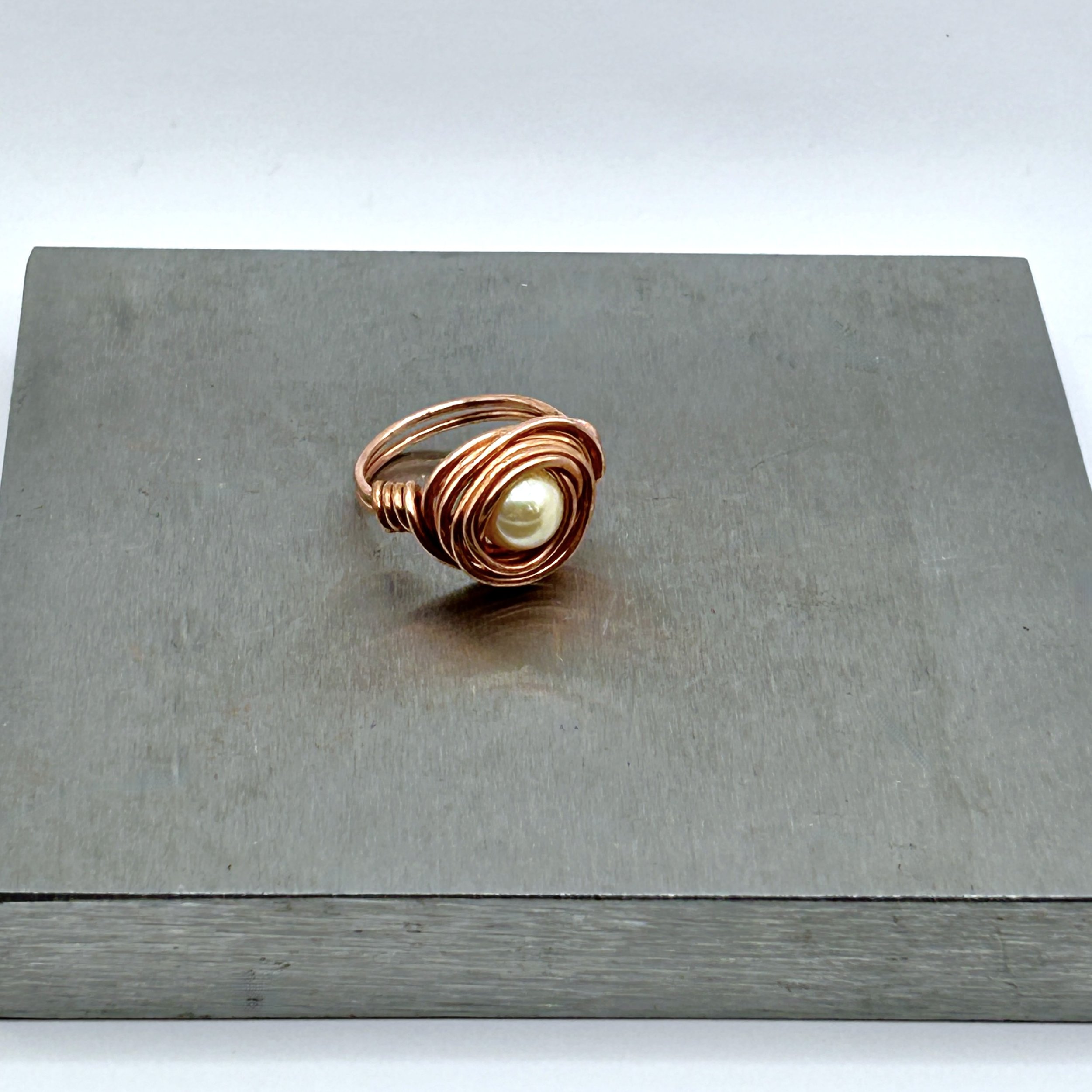 Messy Bun Ring with Acrylic Pearl bead and Copper Metal on metal block top view