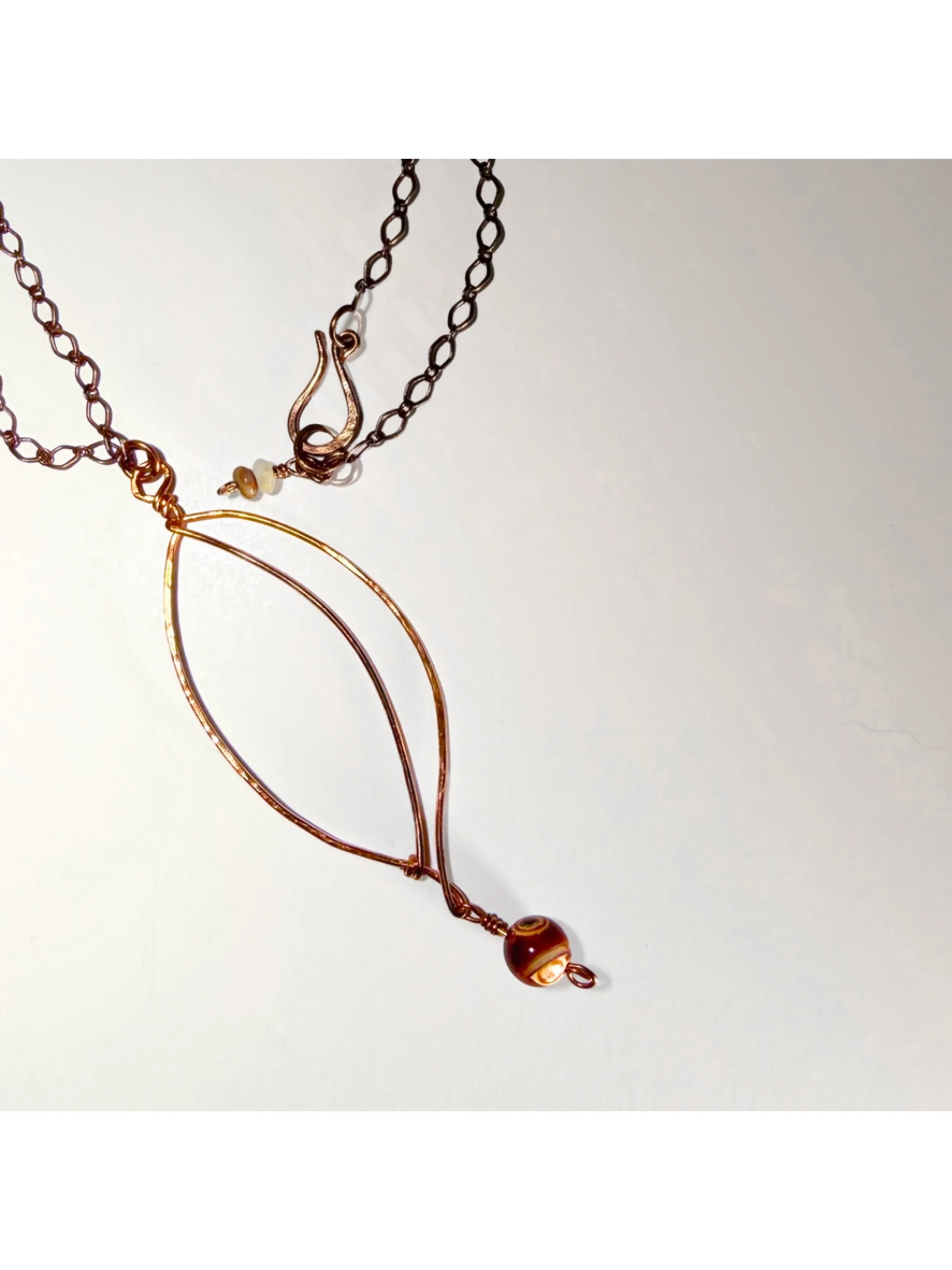 Copper sculpted leaf pendant with gemstone necklace with antiqued copper plated chain on light background