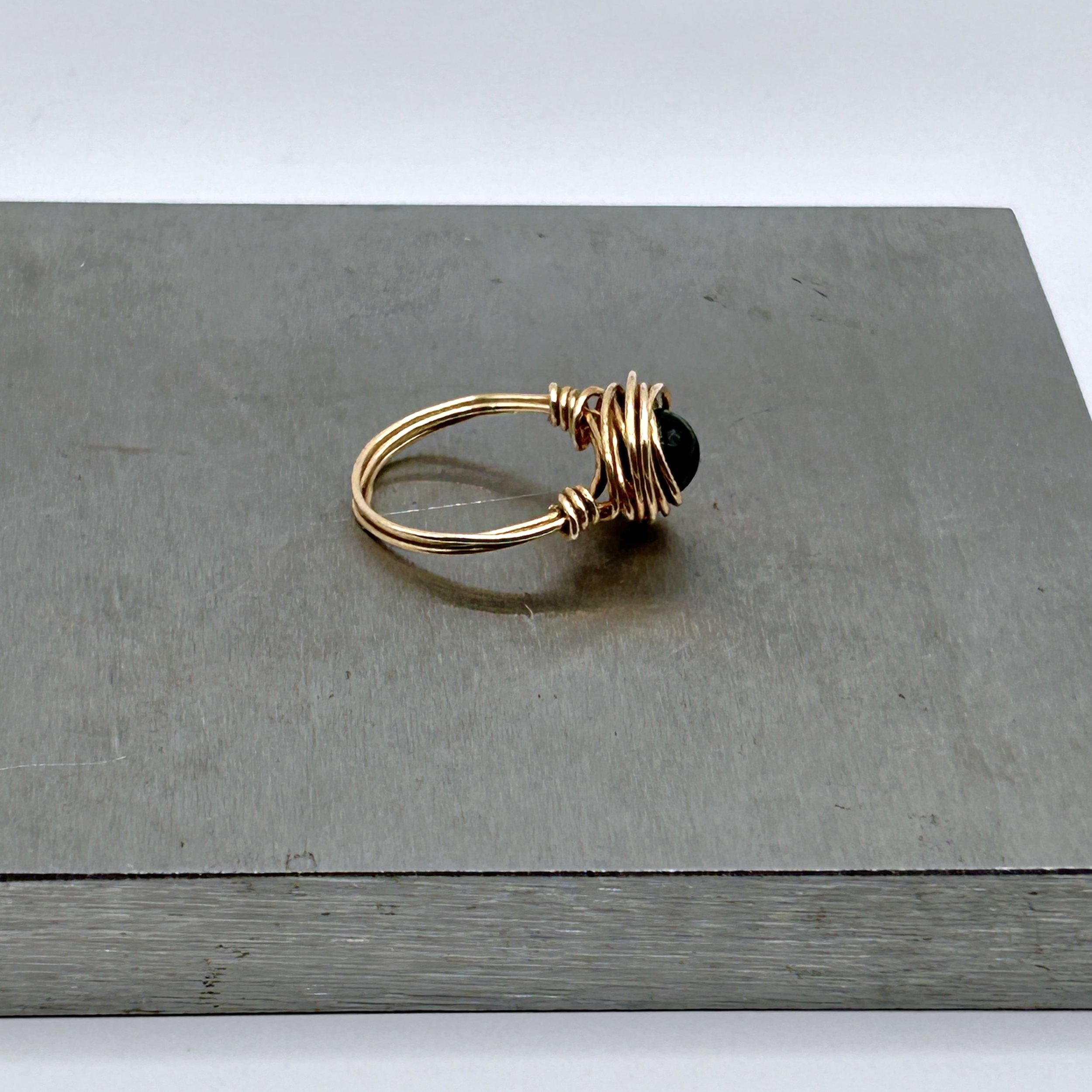 Messy Bun Ring with Black Agate Bead and Jeweler's Brass Metal on metal block side view