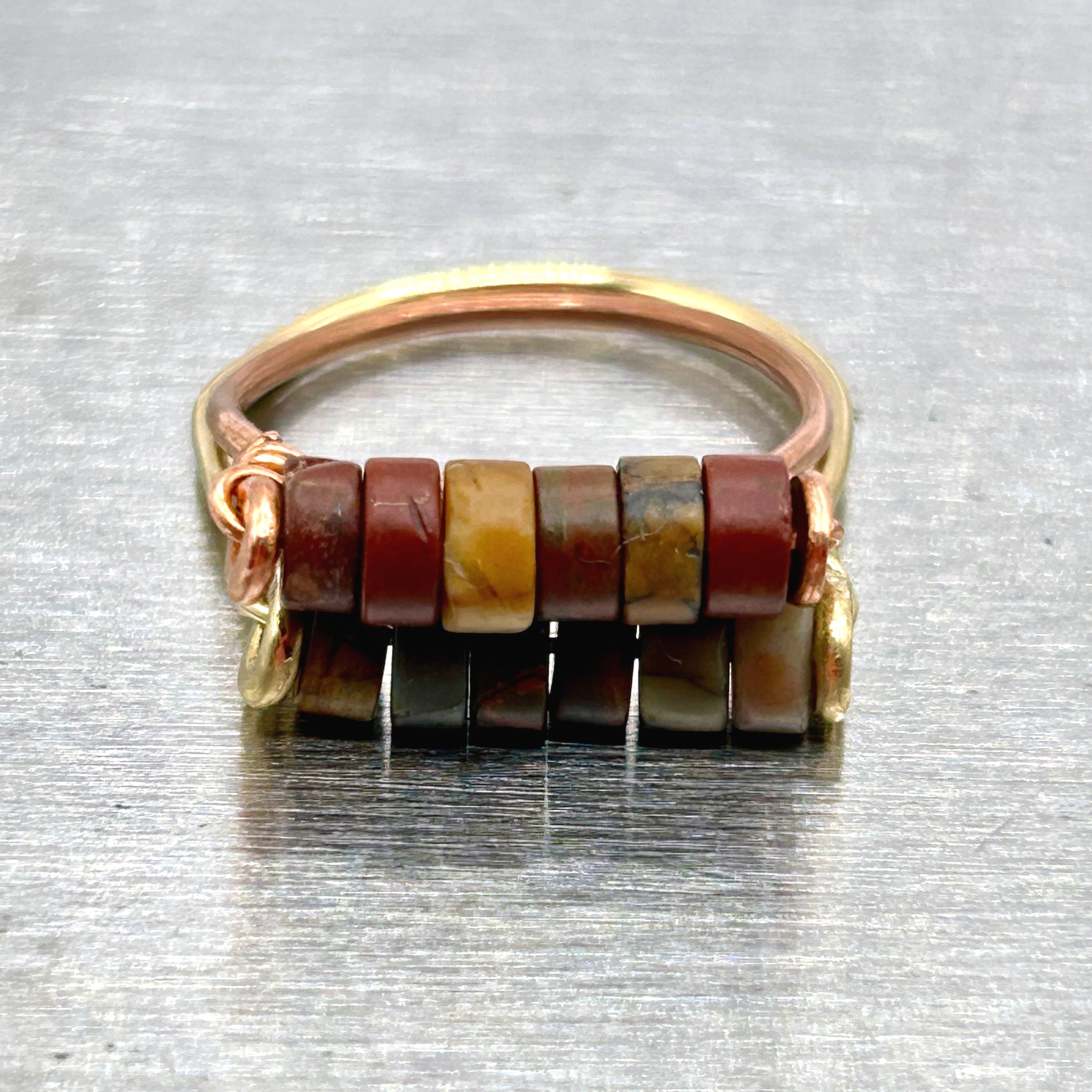 Red Jasper Beads on Copper metal ring on metal block front view