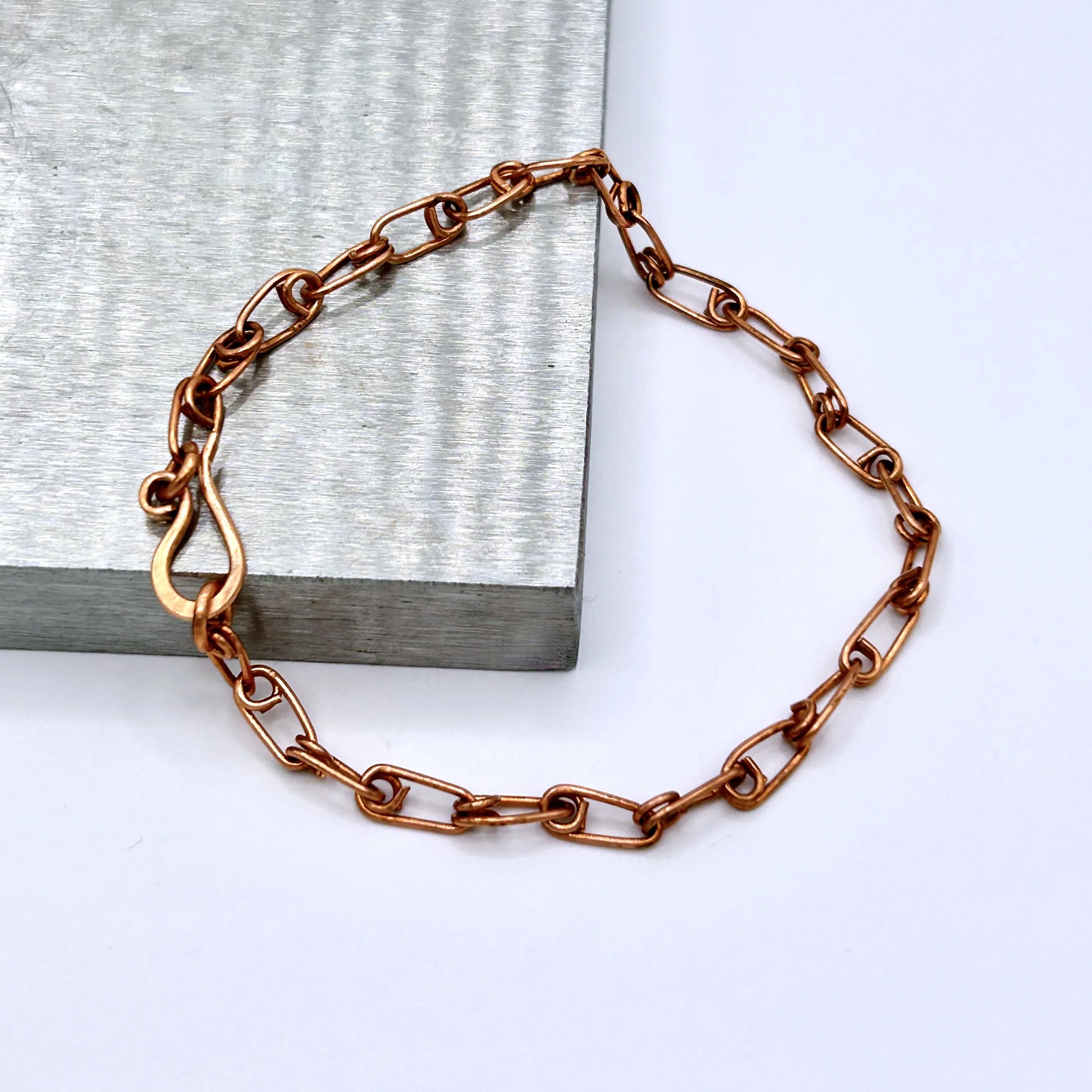 Ellis Copper Metal Safety Pin Link Bracelet on metal block