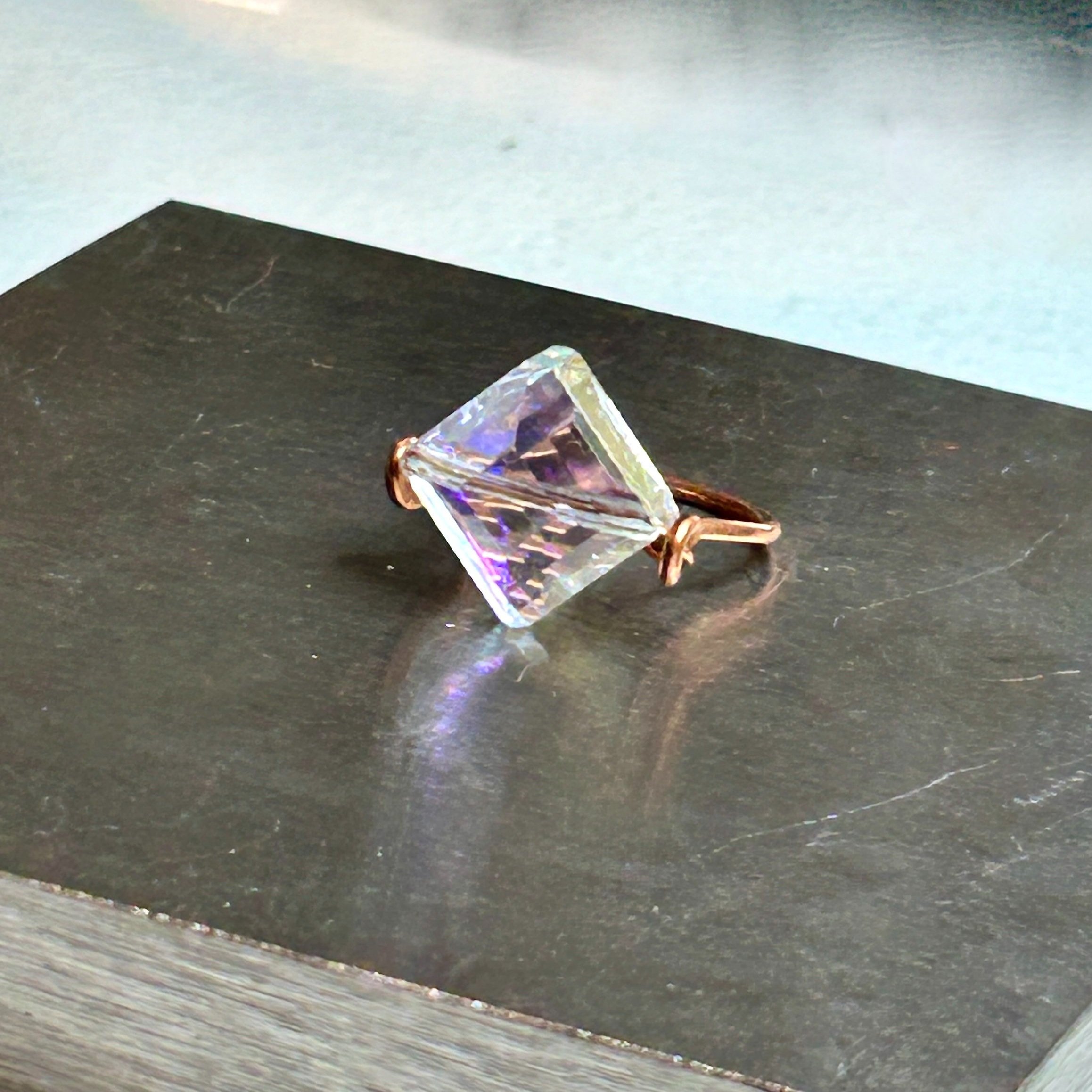 Flat Diamond Shaped Crystal and Copper Metal Viv Ring on metal block front view