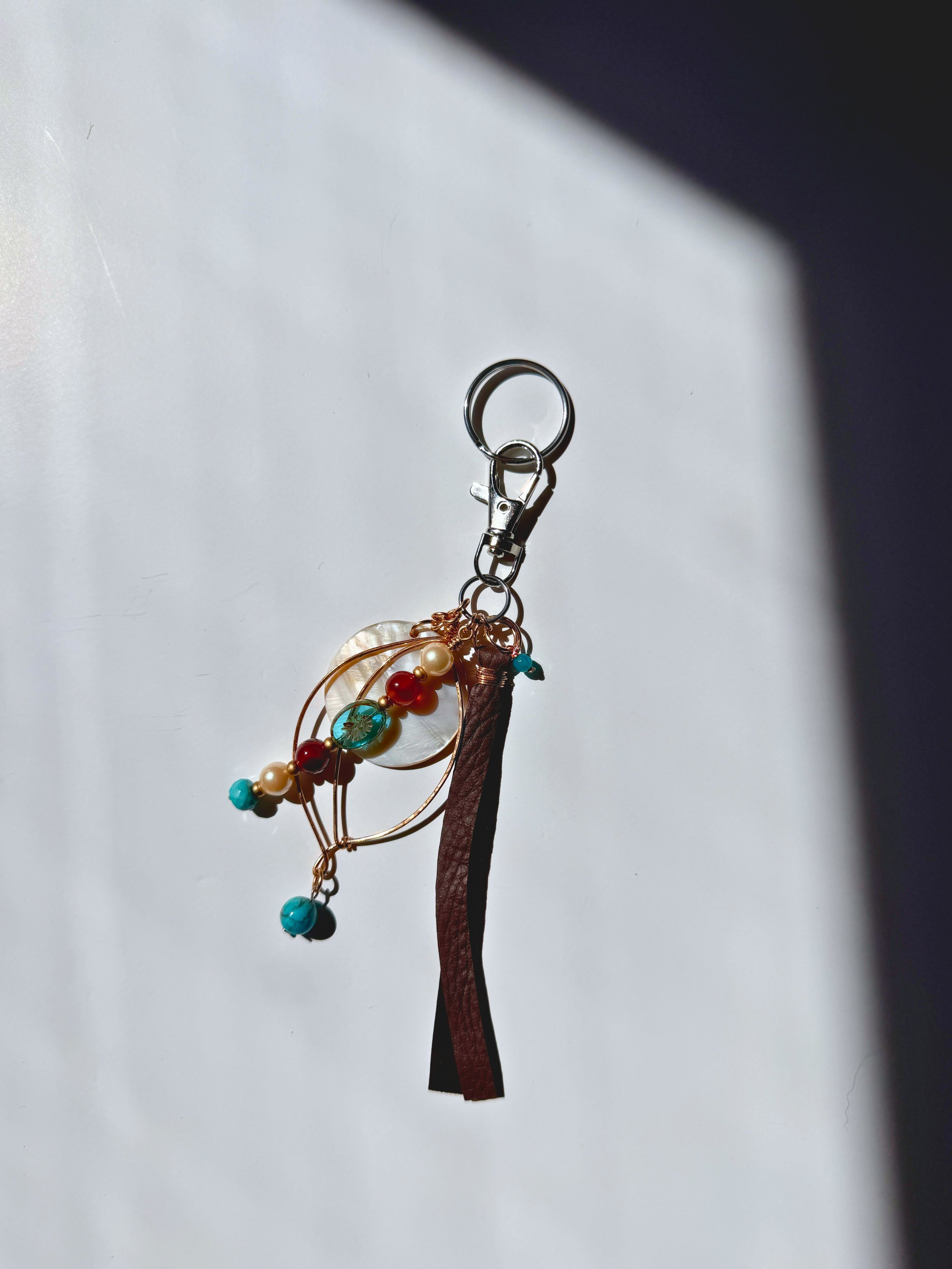 Bronze metal leaf with mother of pearl focal, beads and leather tassel bag charm on light backgroundLeaf Bag Charm