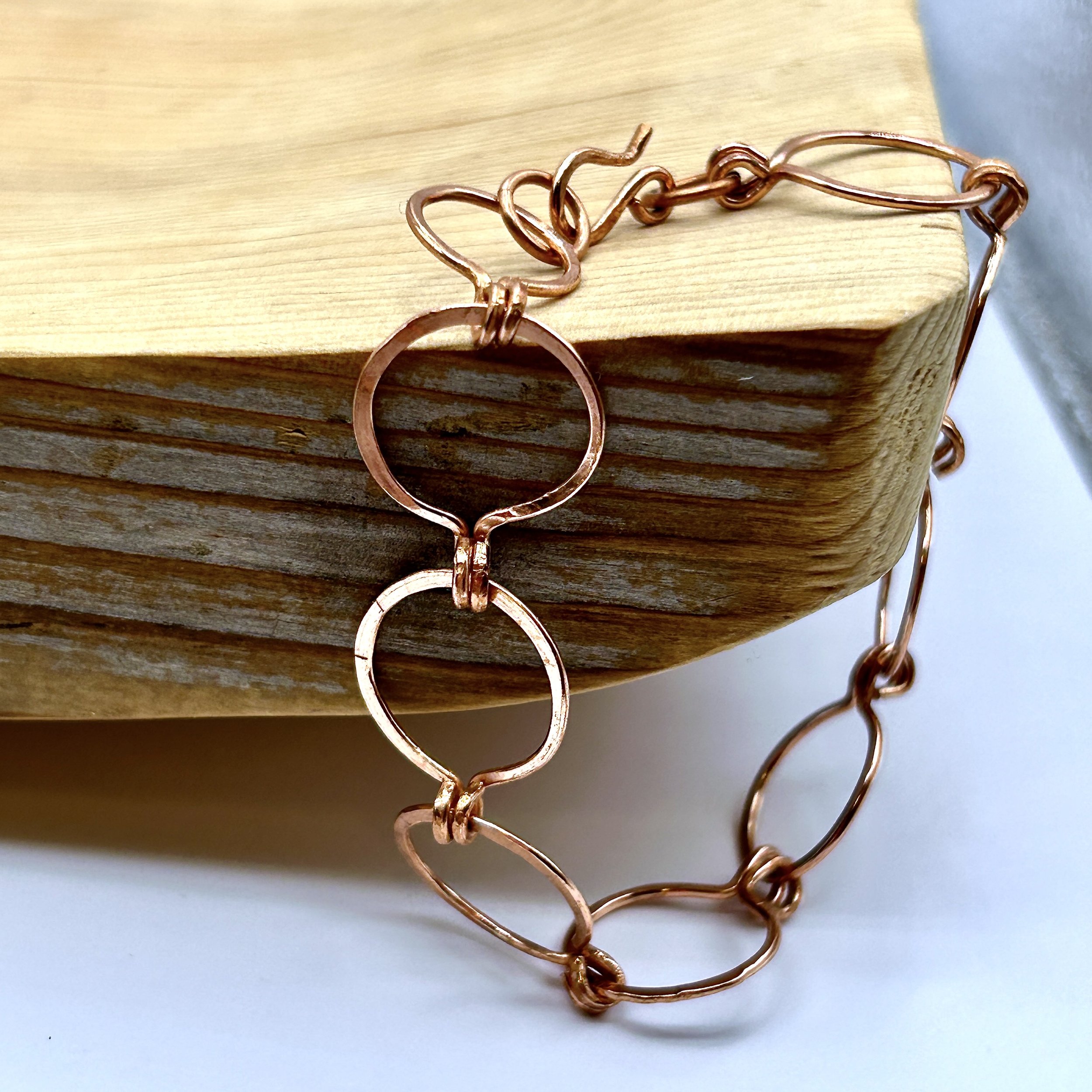 Caroline Open Circles Bracelet in copper metal draped on Wood