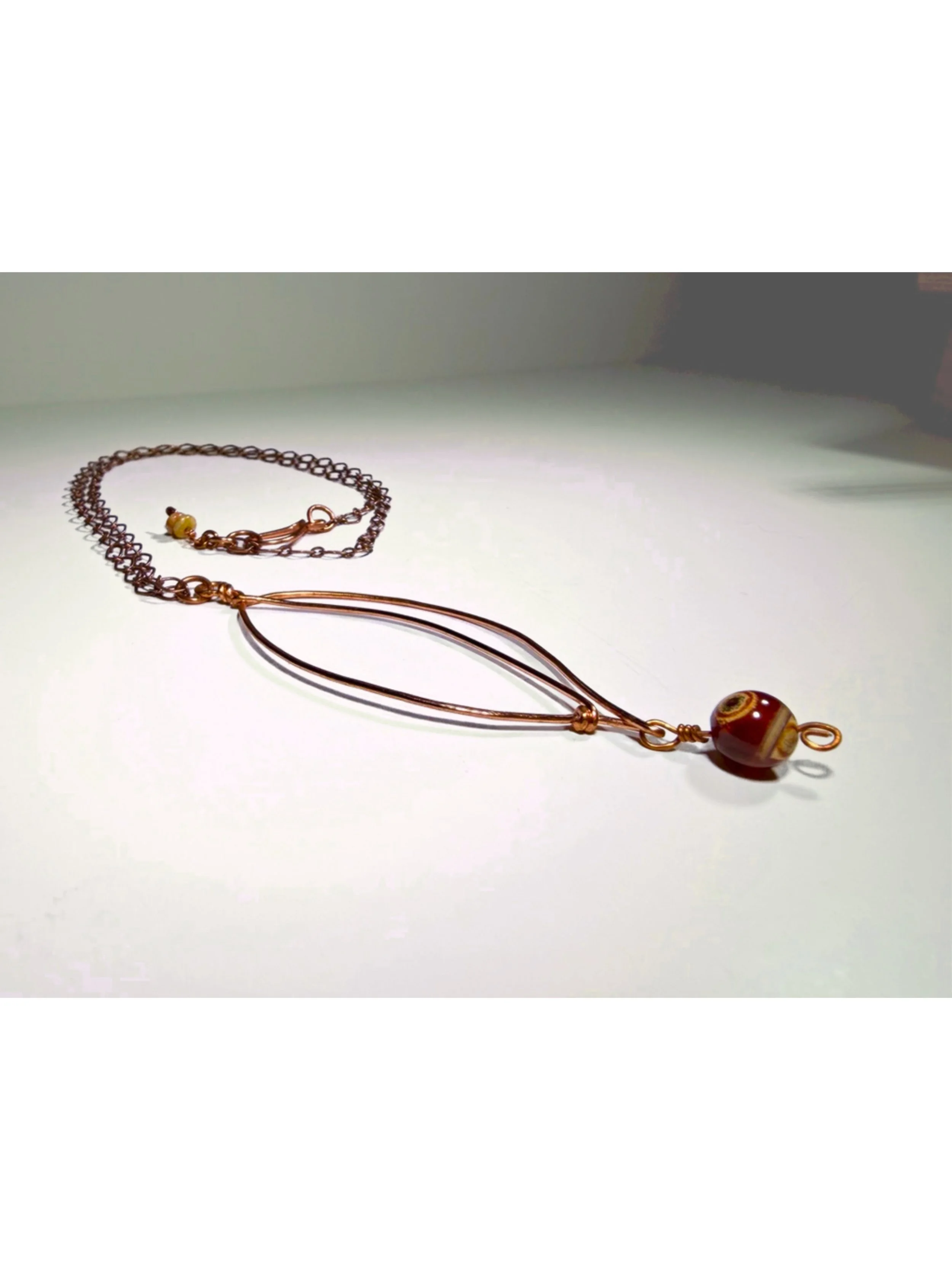 Copper sculpted leaf pendant and gemstone necklace with antiqued copper plated chain on light background