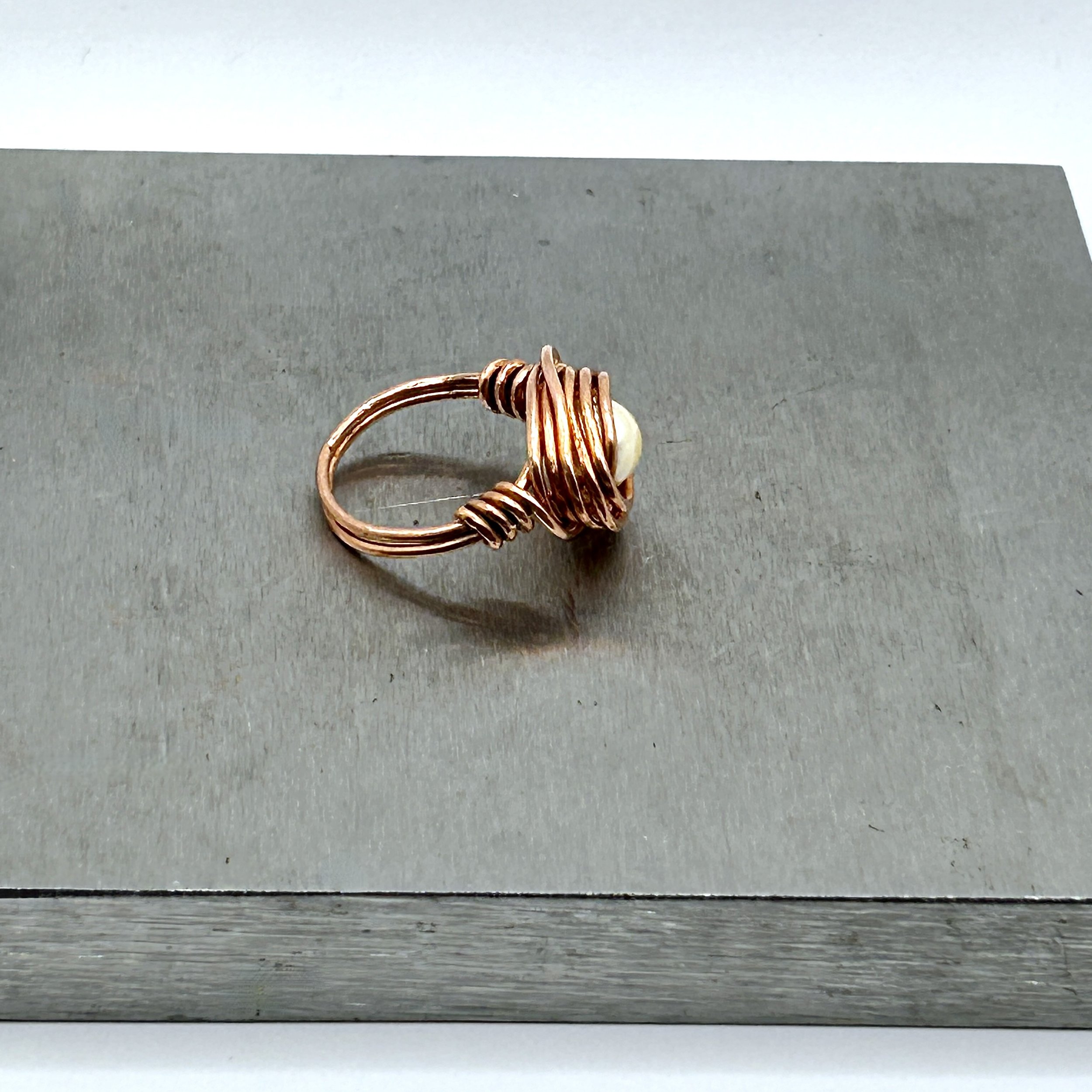 Messy Bun Ring with Acrylic Pearl bead and Copper Metal on metal block side view