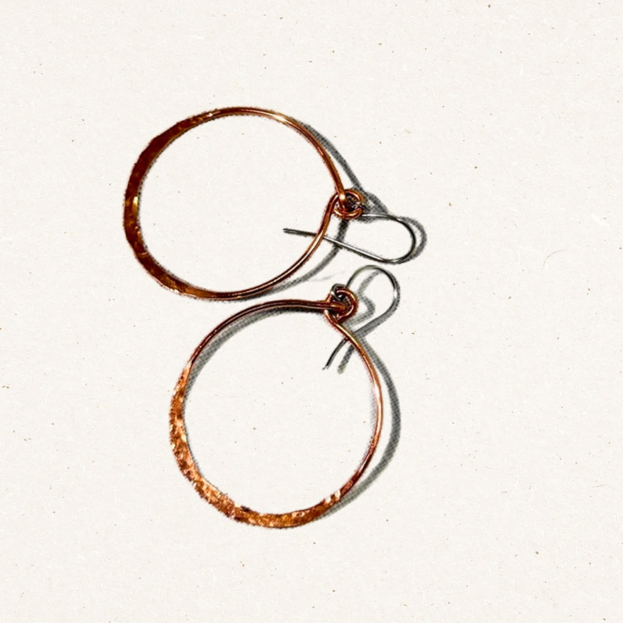 Hammered copper circle earrings on cream background