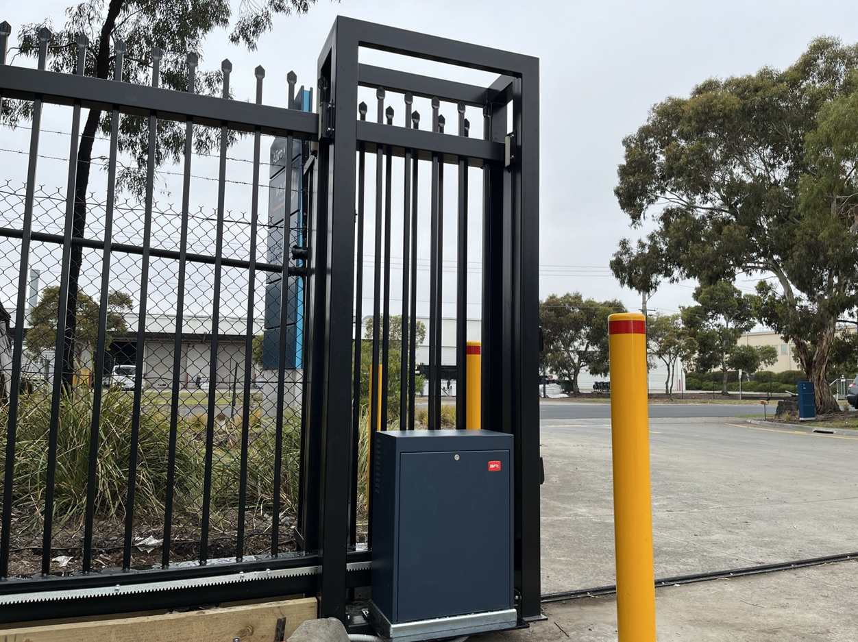 Industrial gate with automatic control box and yellow safety bollards