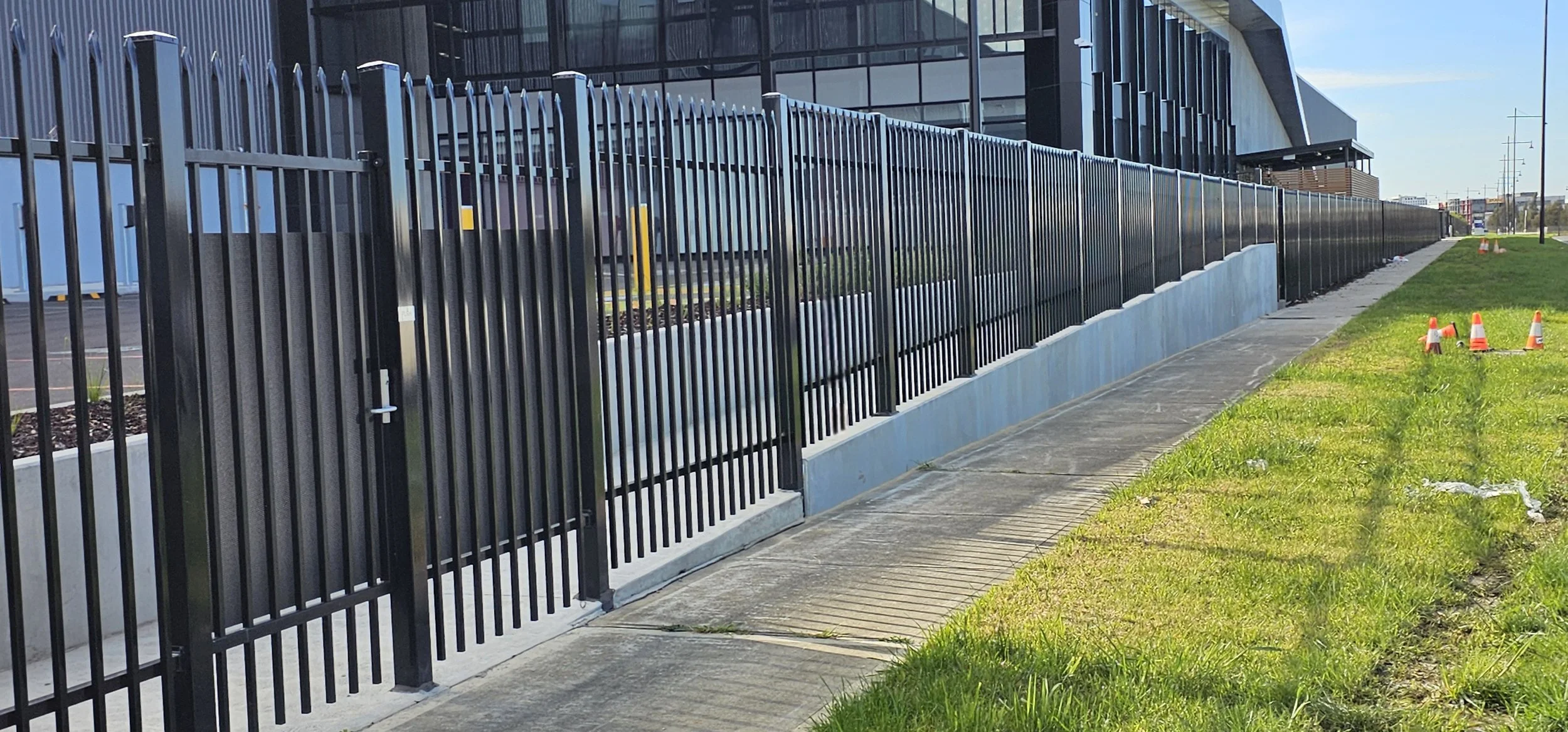 Tall black metal fence with pointed tops along a sidewalk