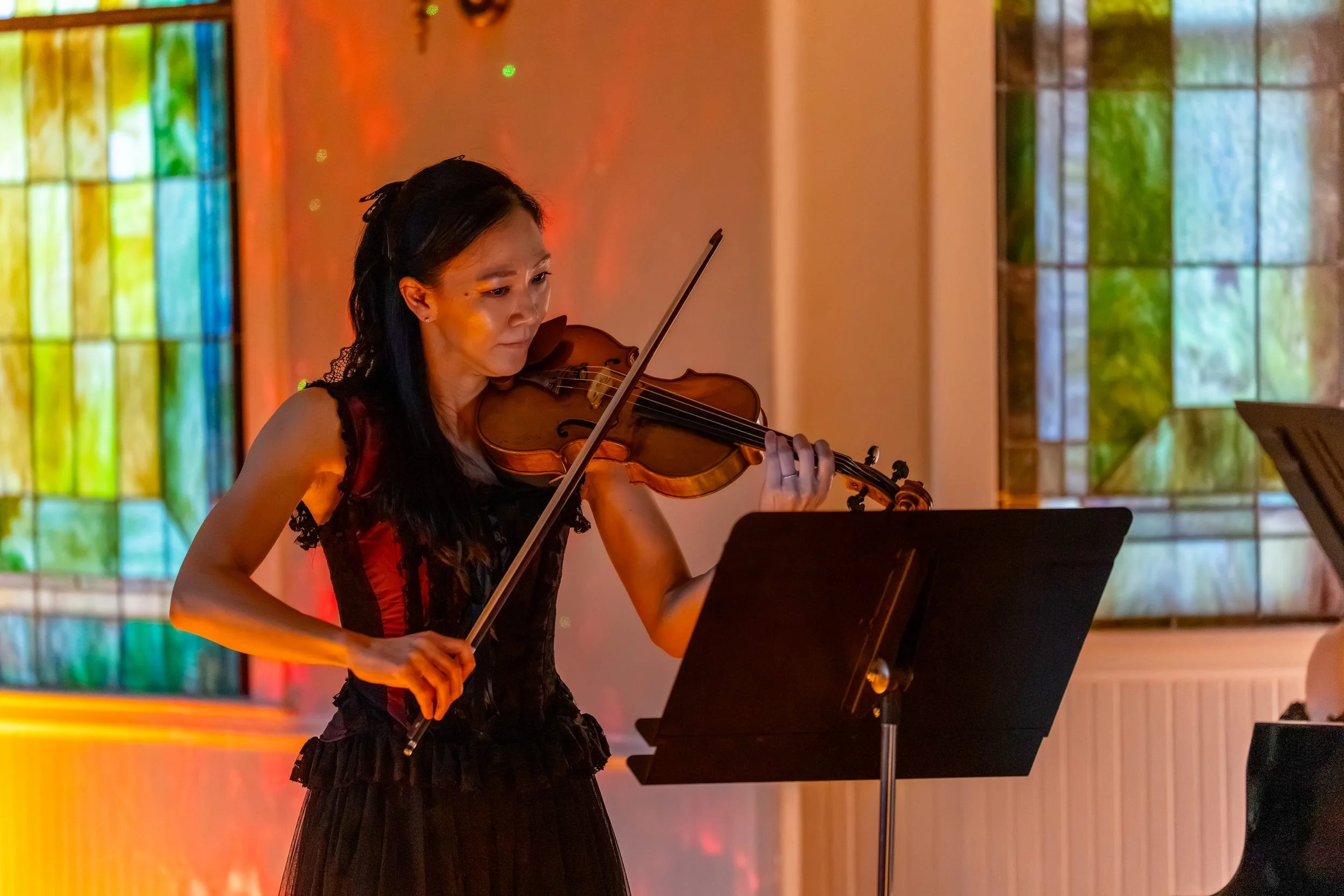 Violinist at a music stand beside a stained glass window