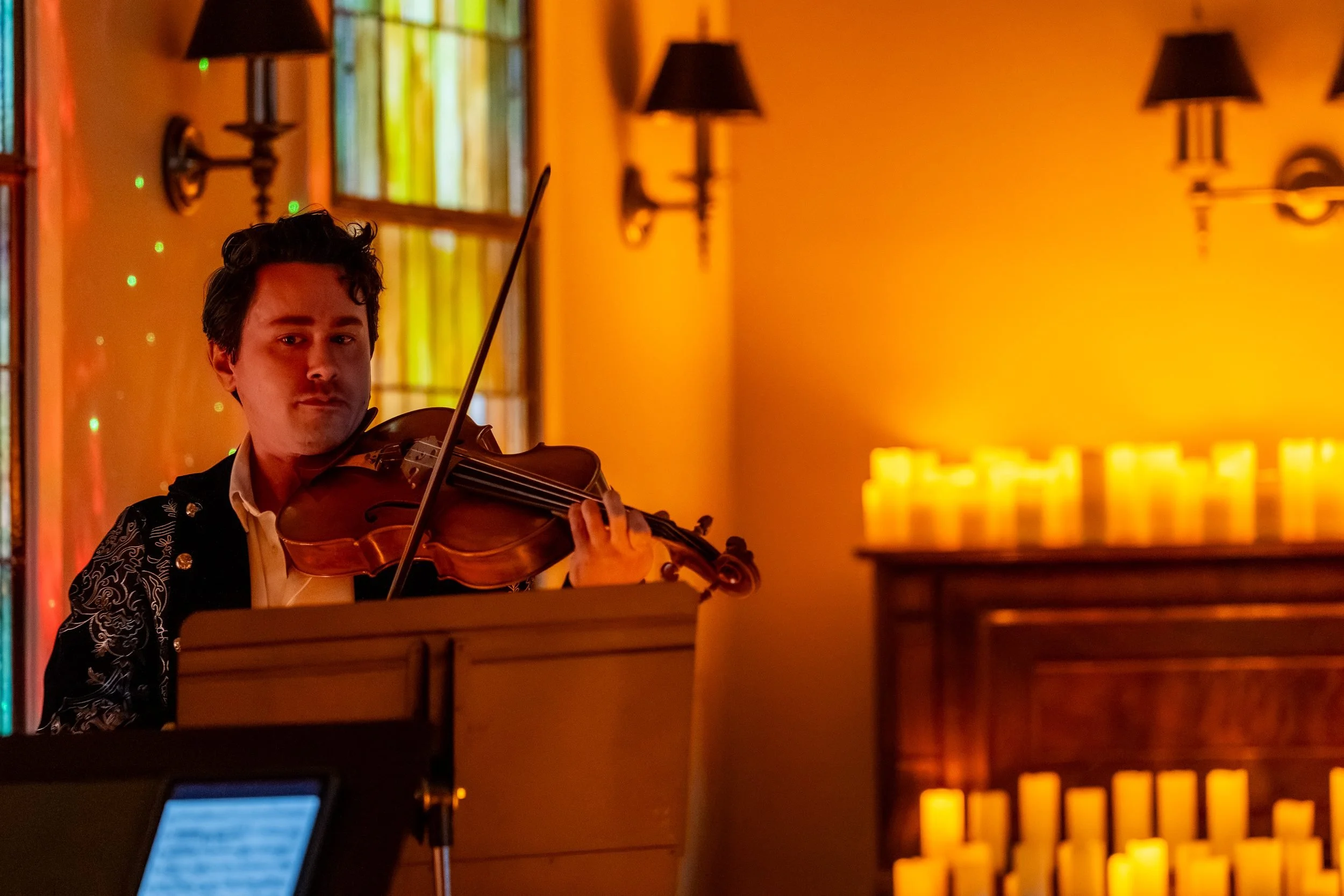 String player with rows of candles behind him