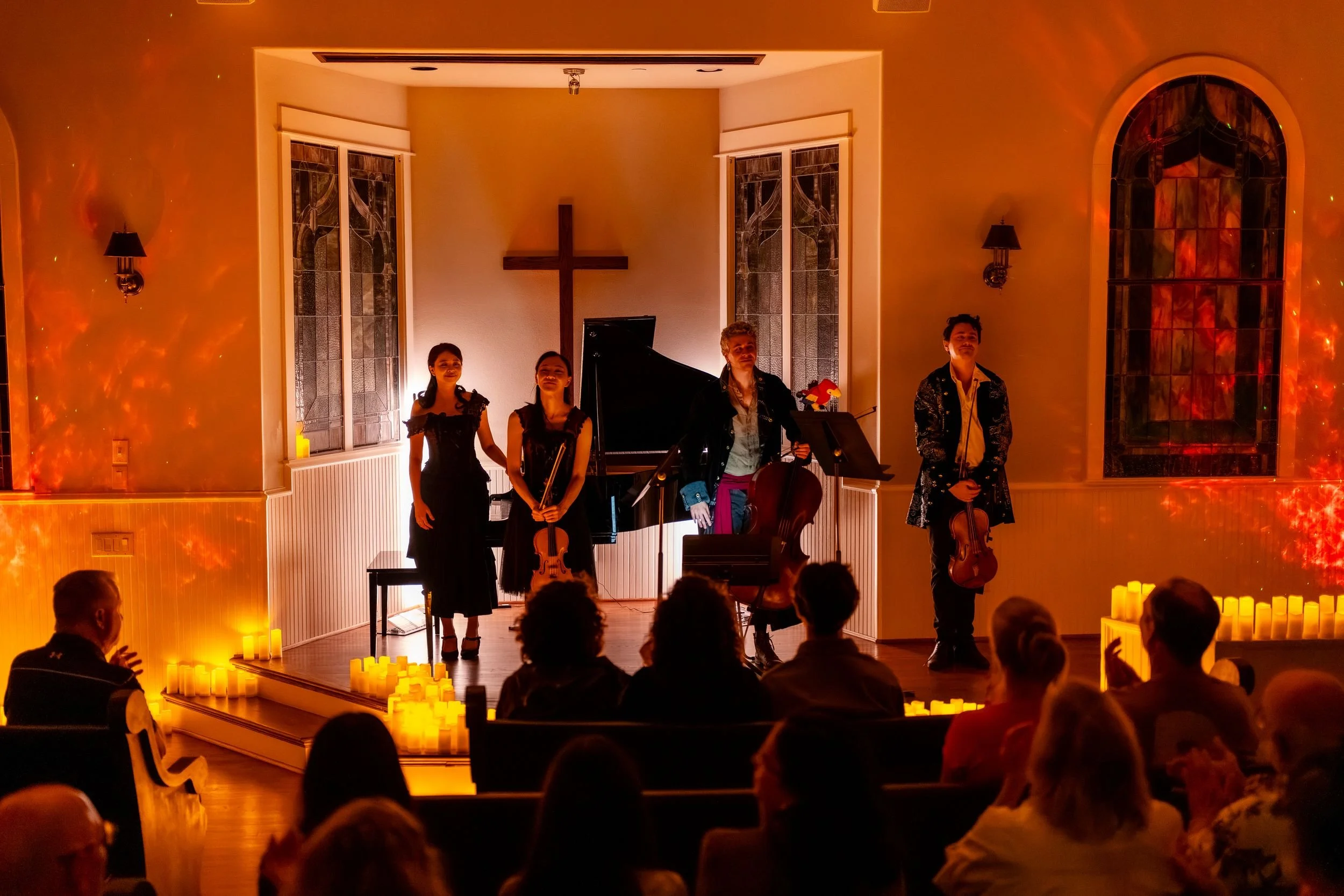 Musicians performing to a full chapel in red and orange light