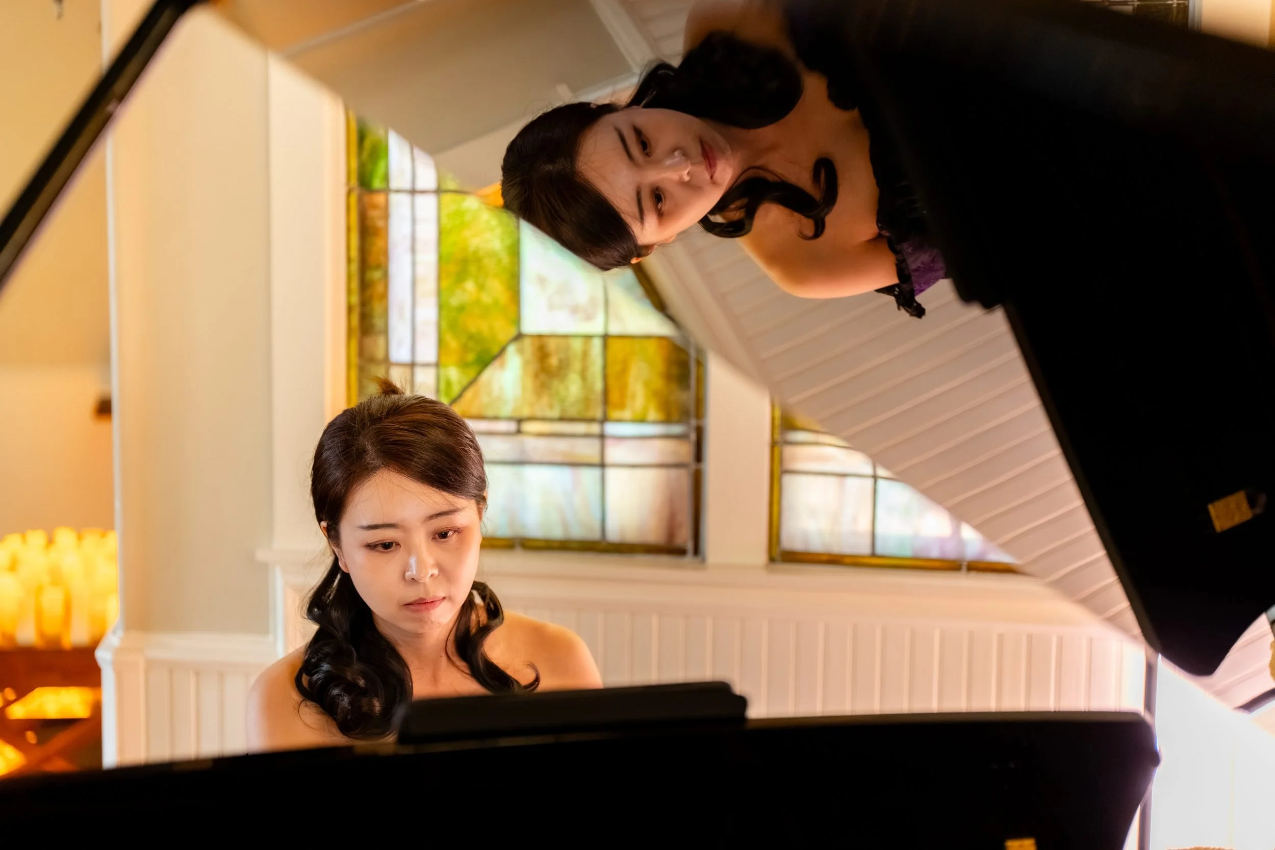 Pianist at the grand piano while a costumed musician leans over the open lid