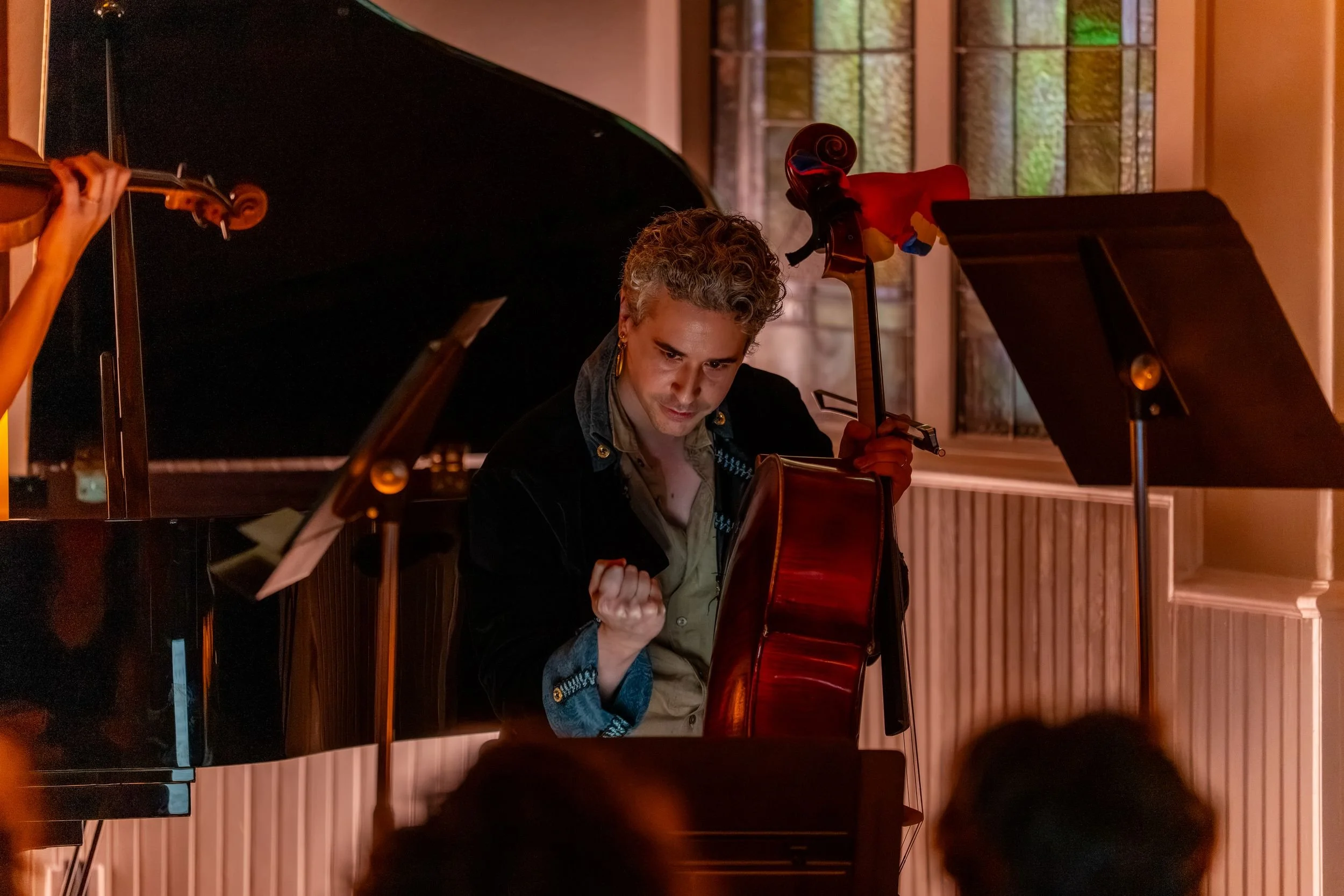 Cellist mid-performance between the piano and music stands